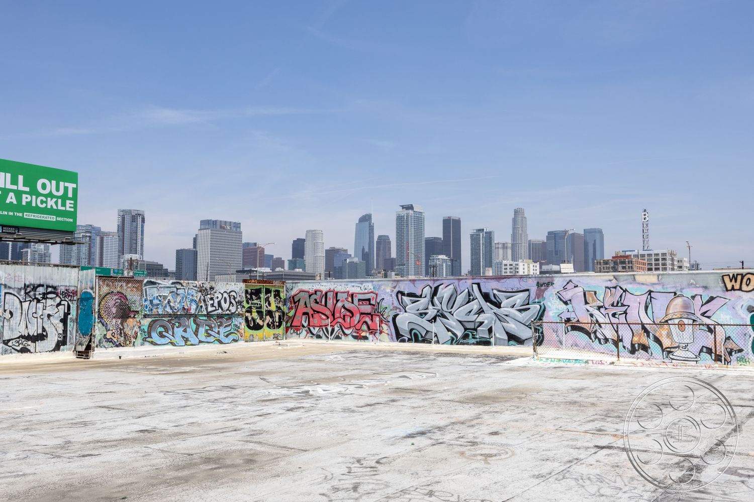 Rooftop 51 - open-air environment, city skyline view, public art space, industrial atmosphere, minimalist architectural style, contemporary cityscape, commercial district setting, exposed concrete rooftop flooring, urban graffiti wall art, steel fence boundary, flat rooftop form, bright daylight illumination, concrete surface texture, surrounding skyscraper backdrop