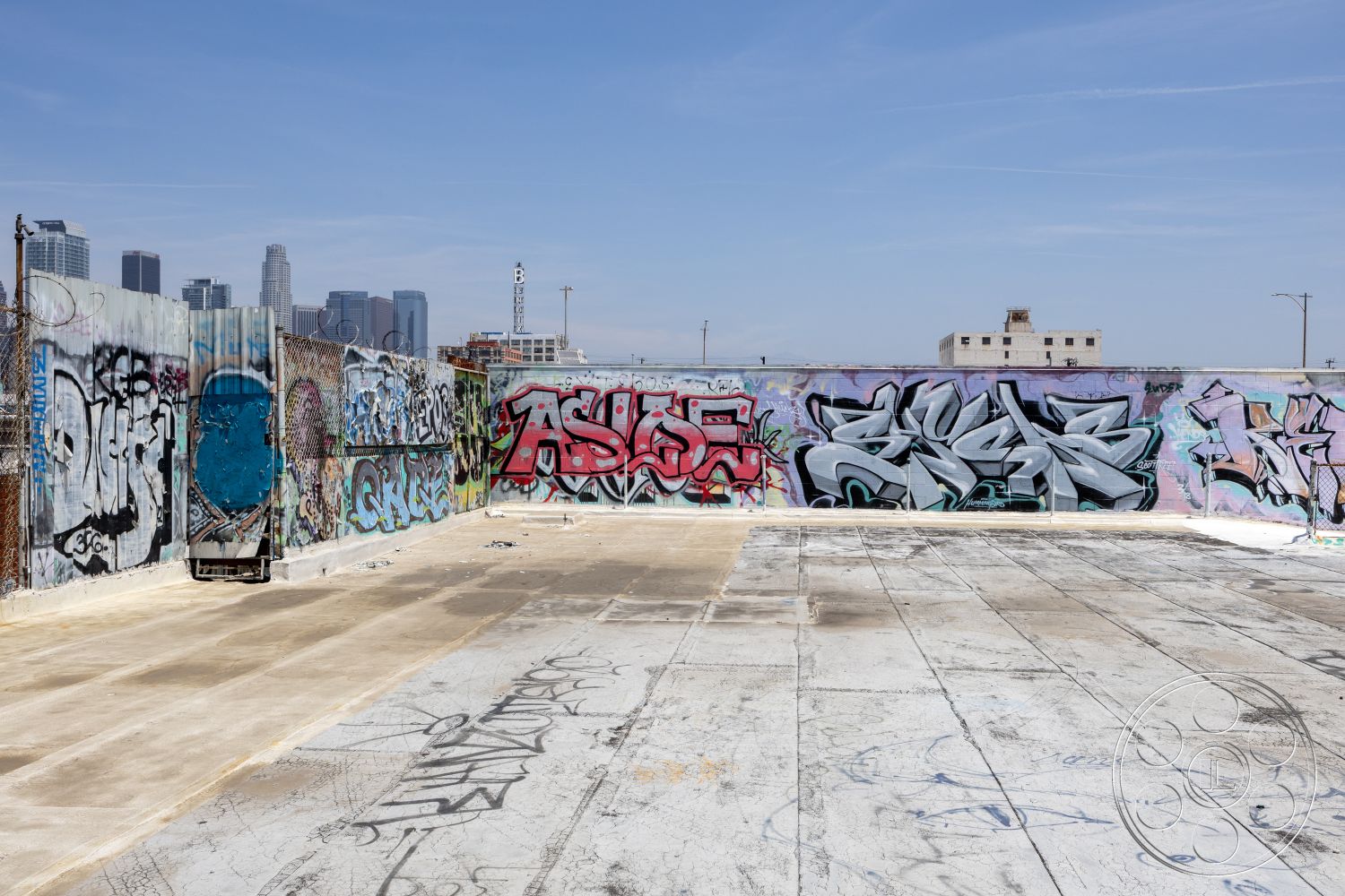 Rooftop 51 - open-air environment, urban skyline view, textured wall treatments, cityscape background, graffiti wall art, industrial setting, graffiti-covered walls, exposed concrete surface, exterior urban landscape, concrete rooftop floor, weathered concrete texture, abandoned rooftop space, metal fence barrier, unfinished concrete area