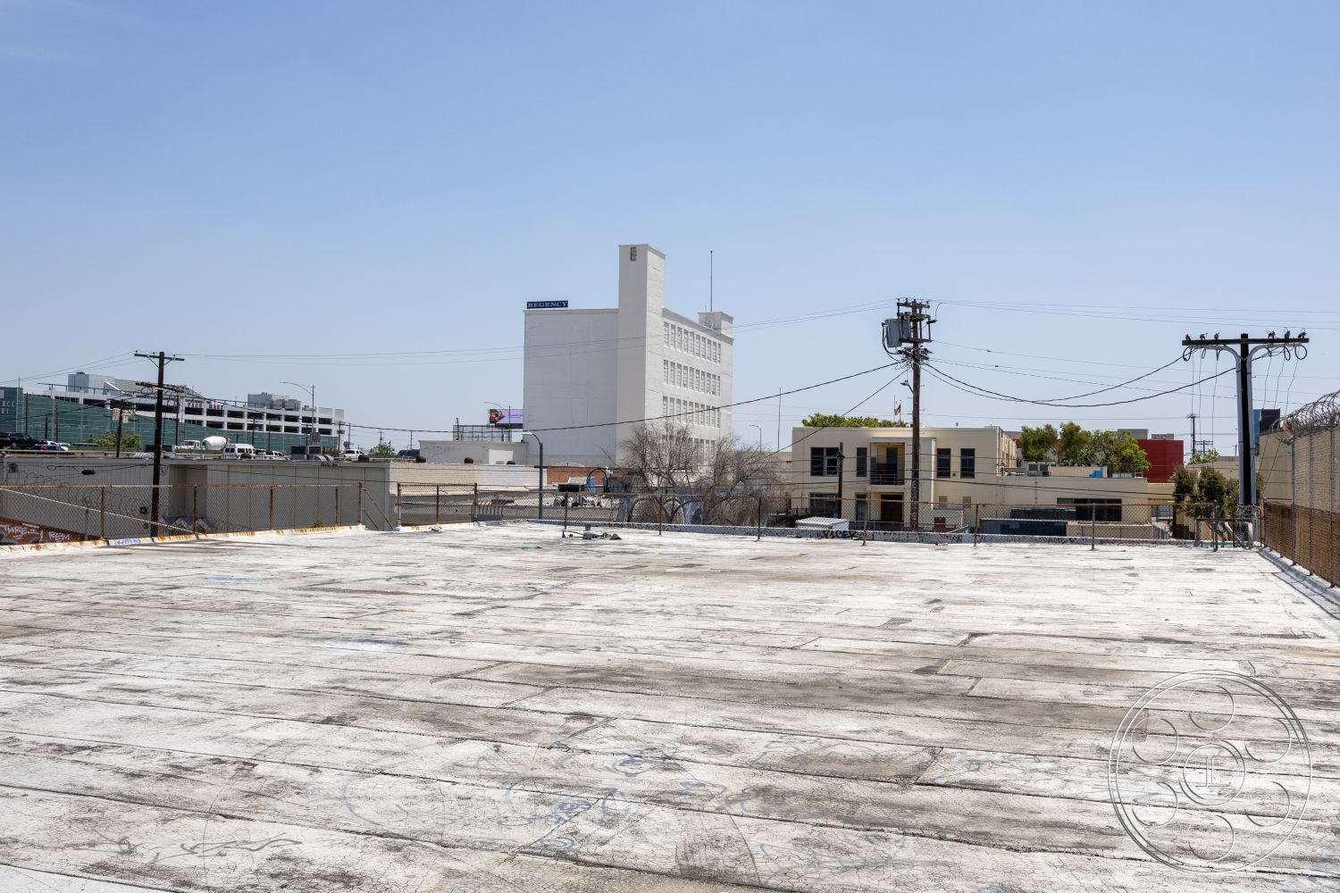 Rooftop 51 - fenced perimeter, surrounding city skyline, commercial building setting, exterior rooftop view, flat roof surface, downtown urban environment, industrial architecture details, utility poles in view, adjacent buildings in background