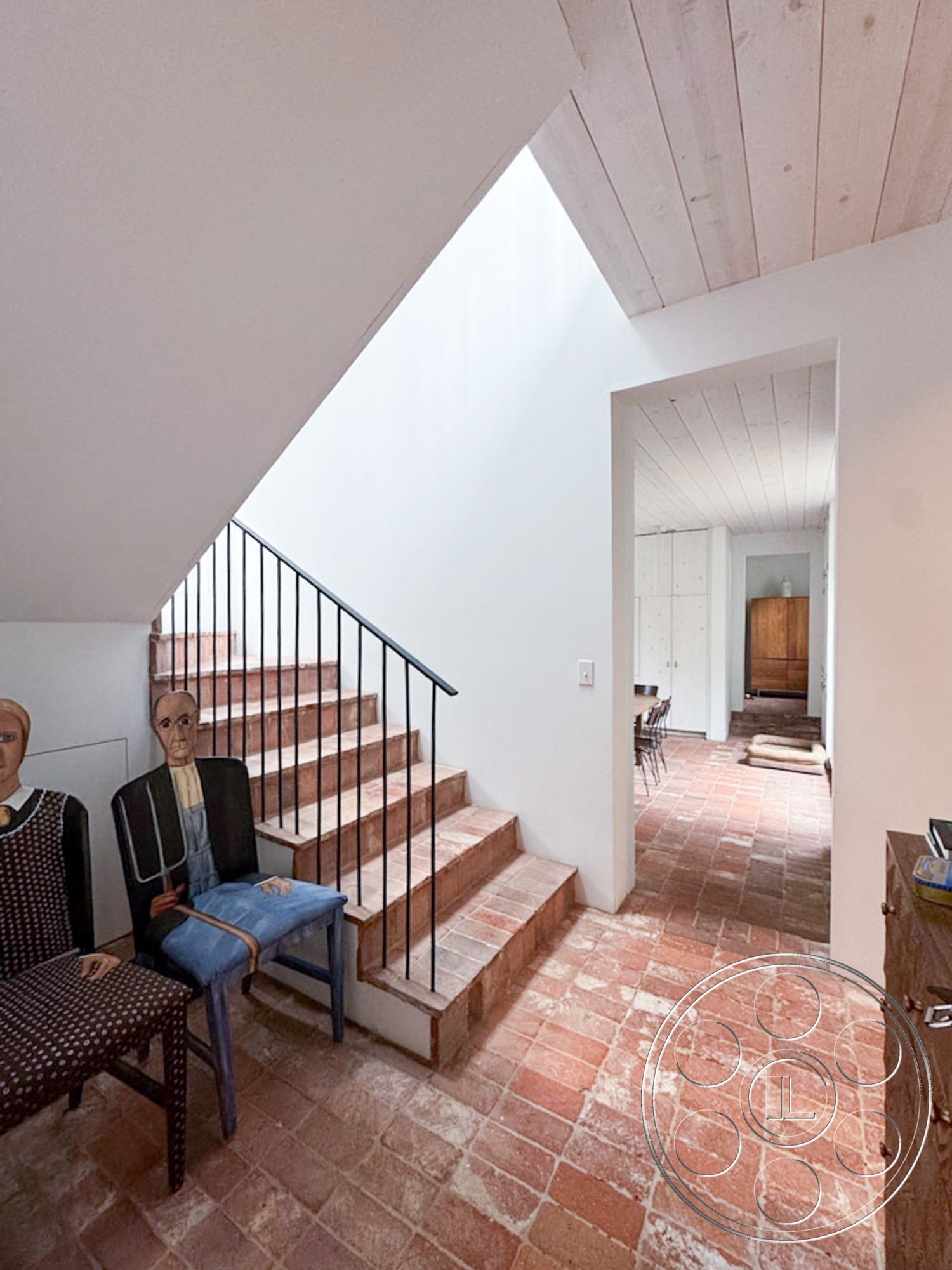 Spanish 165 - earthy color palette, textured plaster walls, terracotta tile flooring, natural light from skylights, minimalist architectural style, geometric shapes in architecture, open-concept interior layout, exposed brick staircase steps, black metal stair railings, light wood ceiling planks, vaulted ceiling in entryway, modern farmhouse interior design