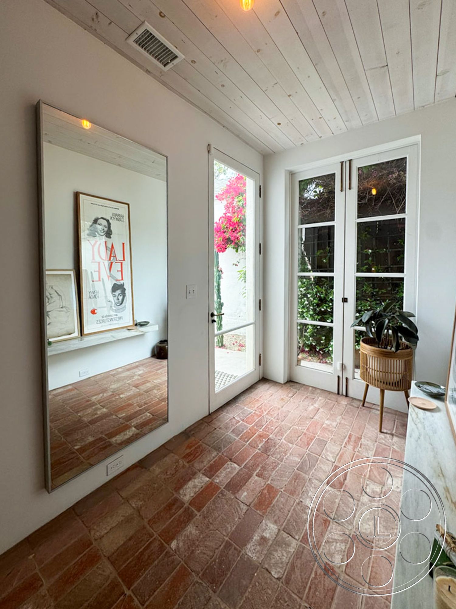 Spanish 165 - contemporary decor, open floor plan, bright and airy atmosphere, natural light from windows, lush indoor plants, metal light fixtures, exposed wood ceiling beams, textured plaster wall, minimalist decor style, white painted walls, interior brick flooring, large mirrors on wall, glass paneled door, functional entryway design, stone shelf surface, vintage artwork accent, garden view from windows, rustic charm details