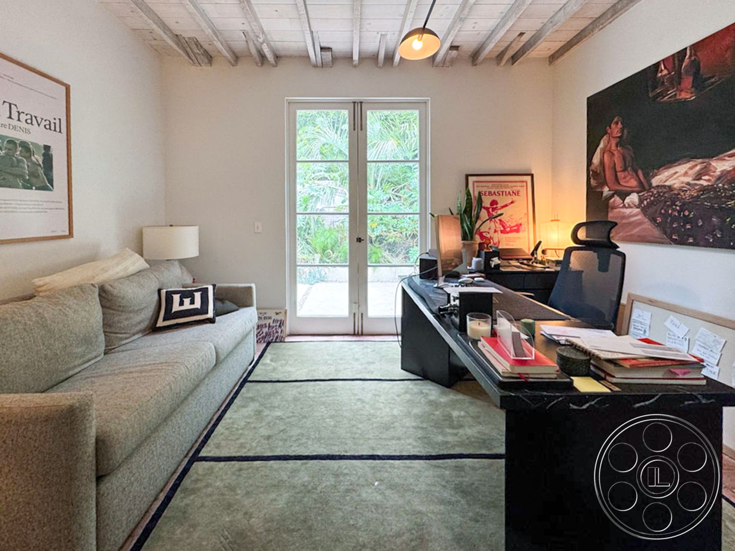 Spanish 165 - contemporary style, glass sliding doors, plant decoration, exposed wood ceiling beams, white painted walls, minimalist decorative elements, hardwood office flooring, modern desk with storage, textured area rug with blue lines, framed artwork on walls, natural light from exterior, private office setting, calm workspace ambiance, functional desk area