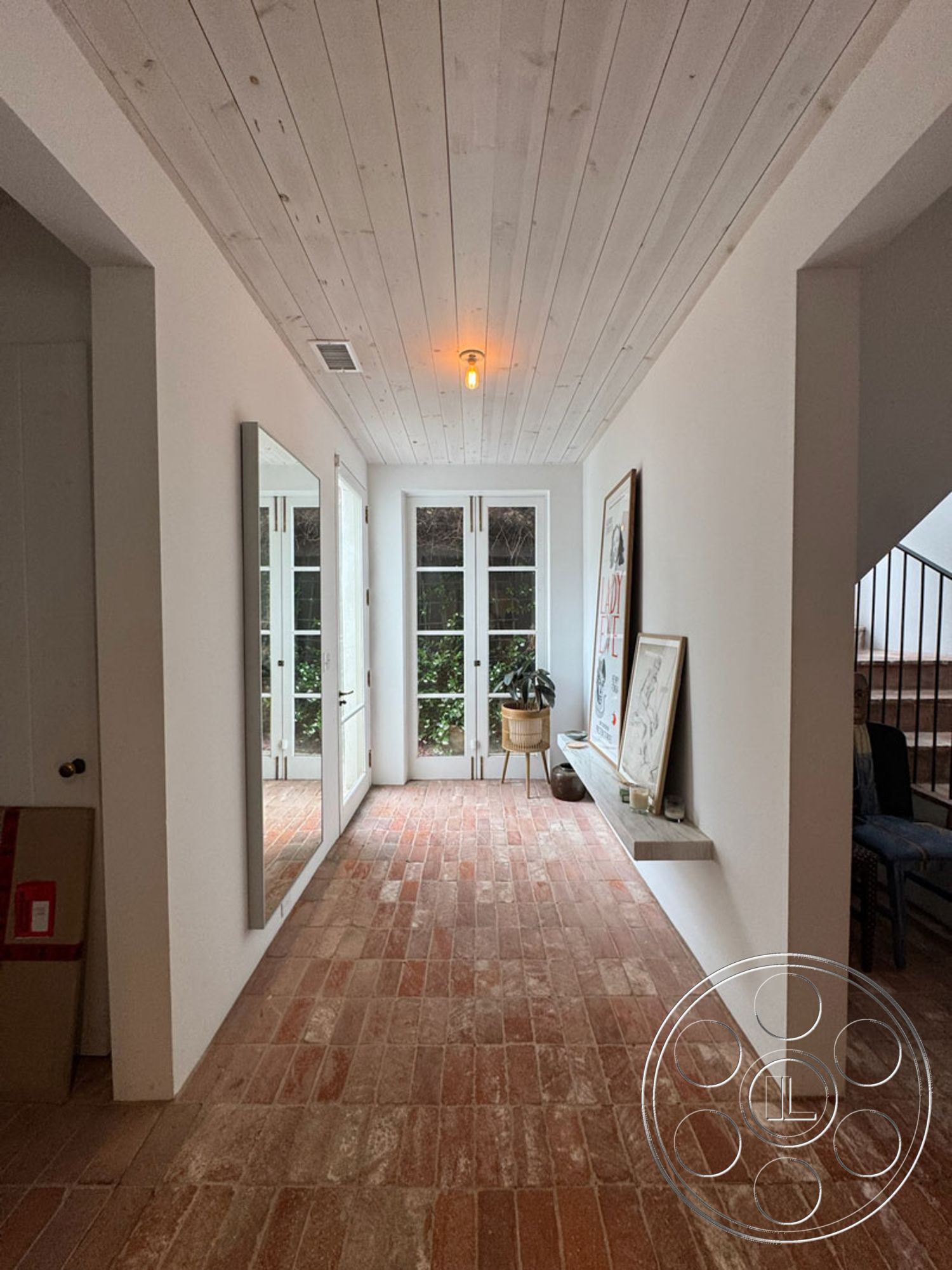 Spanish 165 - minimalist decor, neutral color palette, clean lines, simple lighting fixtures, floor-to-ceiling windows, brick flooring, textured wall finishes, white painted walls, mirror accent wall, exposed wood ceiling planks, natural light entryway, plant corner, open layout hallway, contemporary home entry, inviting foyer space, geometric shapes in design