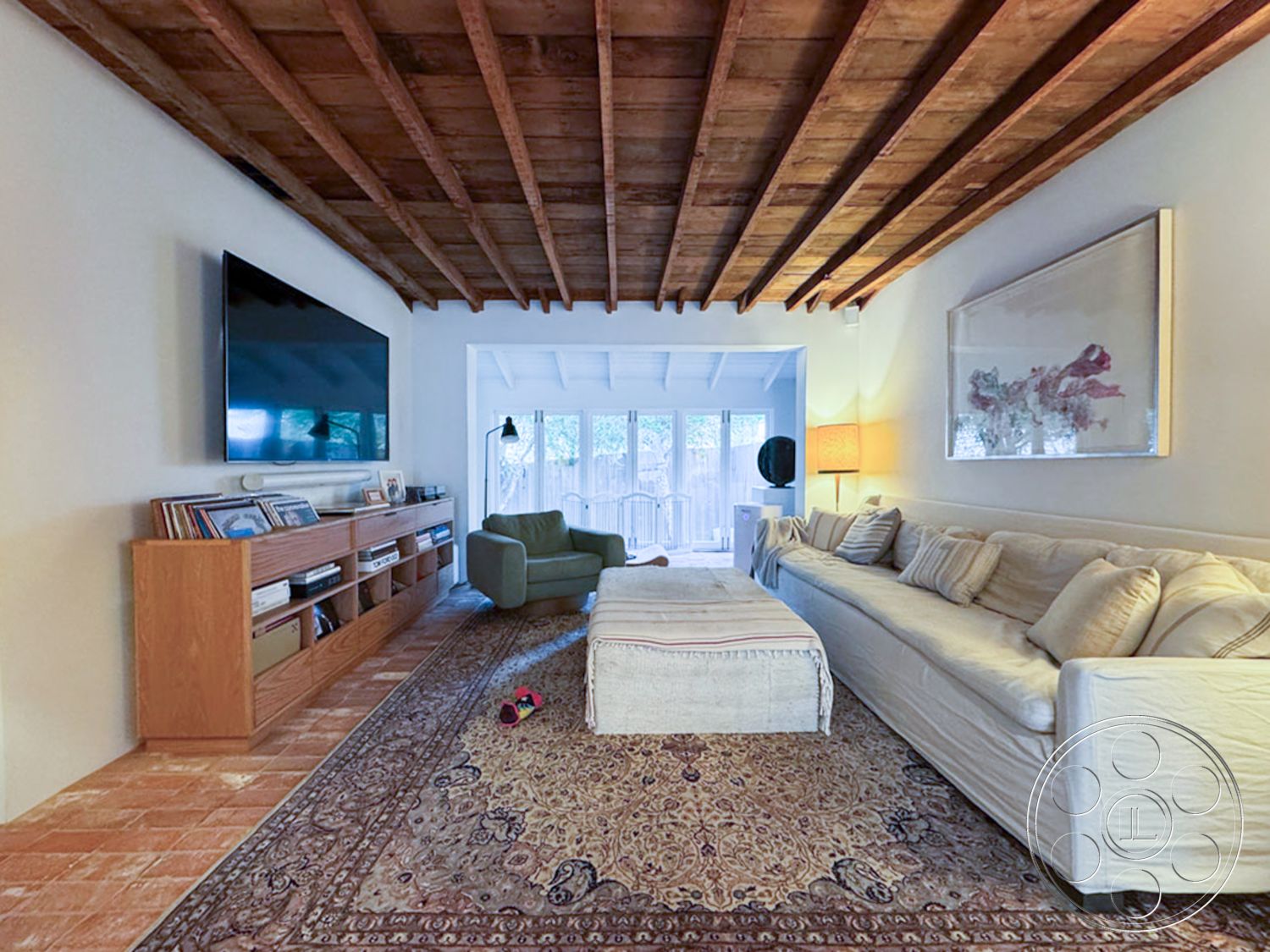 Spanish 165 - exposed wood ceiling beams interior, natural light-filled space interior, open floor plan living room interior, light hardwood flooring interior, textured white walls interior, modern media console interior, rectangular area rug interior, overstuffed sofa with decorative pillows interior, floor-to-ceiling glass doors interior, green accent chair interior, table lamp with fabric shade interior, minimalist decor accents interior