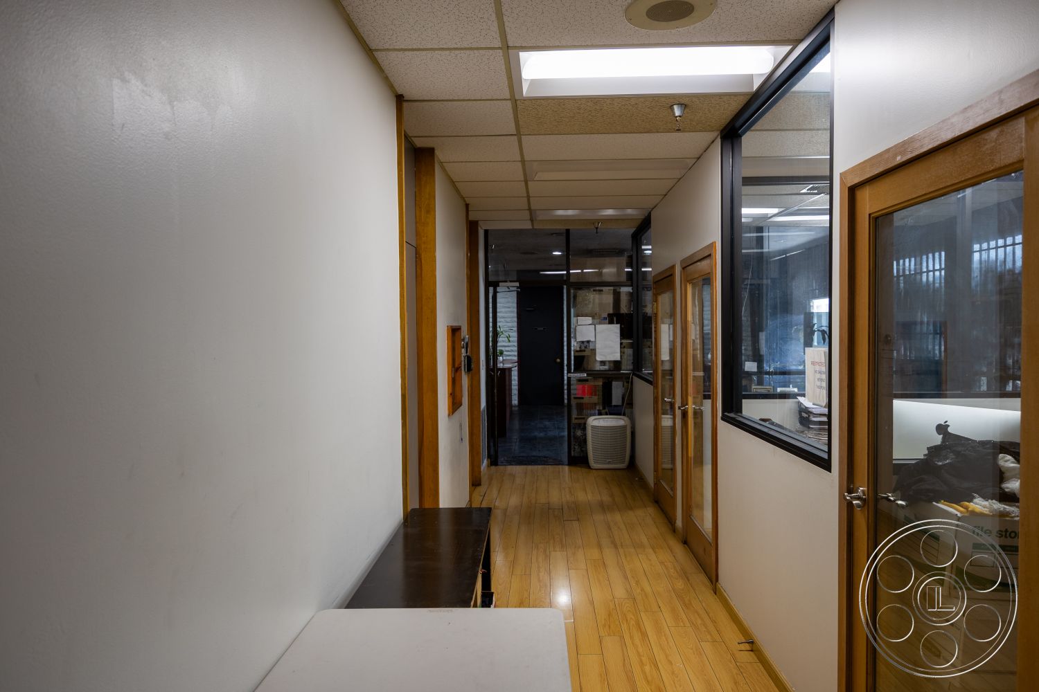 Warehouse 61 - minimalist design elements, wood-framed windows, laminate wood flooring, acoustic ceiling tiles, glass partition walls, interior hallway, white painted walls, built-in shelving units, modern office layout, framed glass office doors