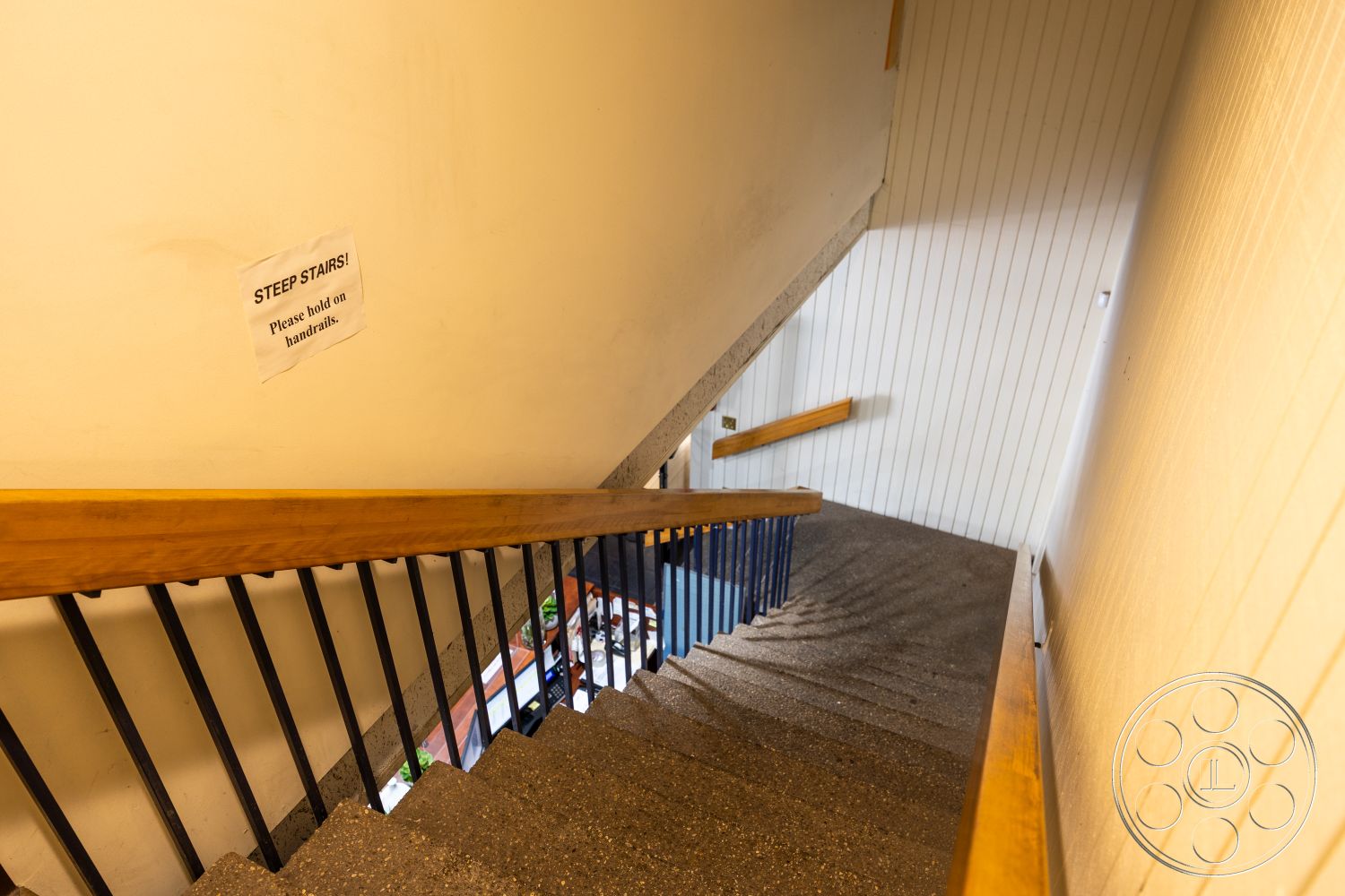 Warehouse 61 - textured plaster wall finish, exterior concrete stair steps, interior wooden handrail, interior blue metal railings, exposed concrete stair treads, interior wall with warning sign, natural wooden accent in staircase, industrial-style staircase design, steep staircase design, architectural detail with handrails, minimalist interior staircase, functional staircase layout