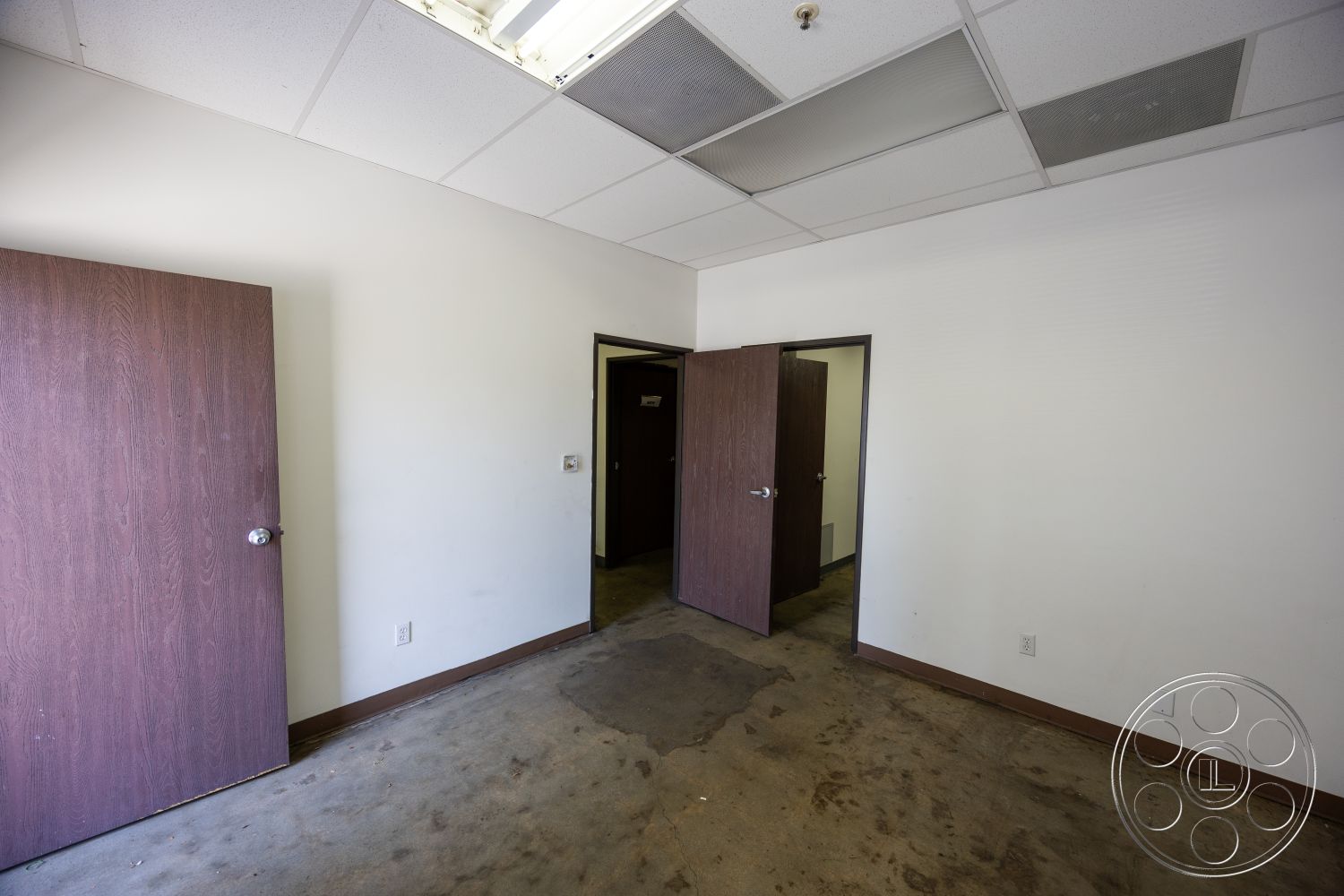 Warehouse 61 - minimalist aesthetic, minimalistic design, office environment, commercial setting, plain white walls, drop ceiling tiles, fluorescent ceiling lights, interior concrete floor, exterior walls painted white, wood veneer doors, textured plaster interior walls, standard office layout, linear floor plan, furniture ready space, partition wall openings
