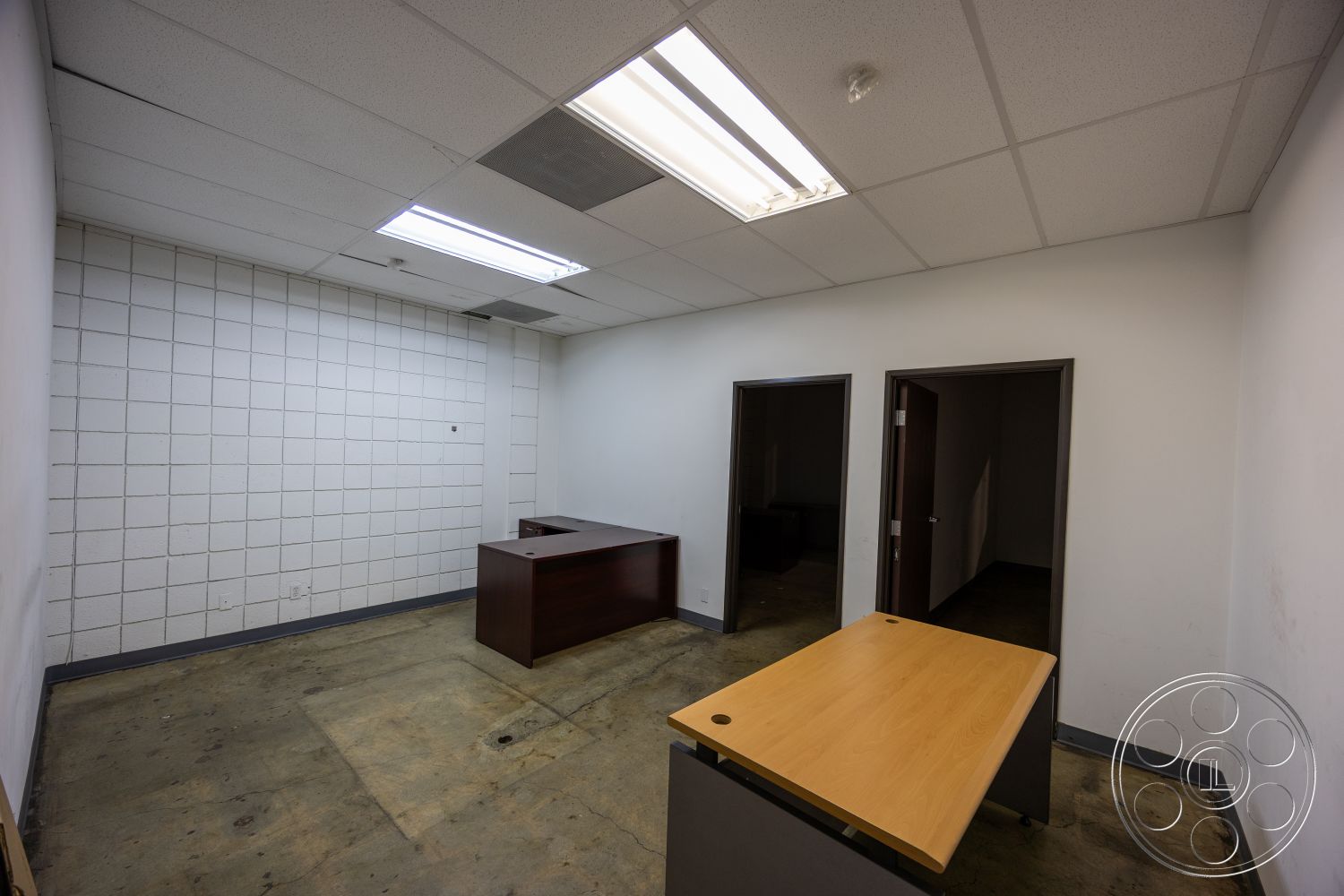 Warehouse 61 - minimalist design, open floor plan, concrete floor, functional workspace, painted drywall walls, interior office space, commercial building setting, drop ceiling with fluorescent lighting, wood laminate reception desk, HDF table surface, double door entrance
