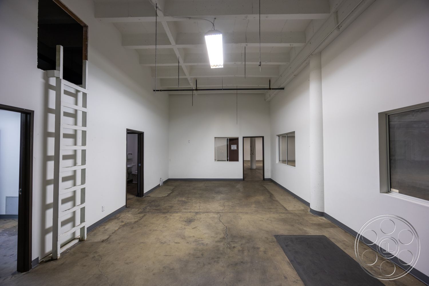 Warehouse 61 - neutral color palette, minimalist design elements, large windows for natural light, floor-to-ceiling windows, high vaulted ceilings, white painted walls, open floor plan interior, functional workspace layout, exposed concrete flooring, metal ceiling beams, industrial style space, concrete support columns, simple ladder access, panelled interior doors, modular design potential
