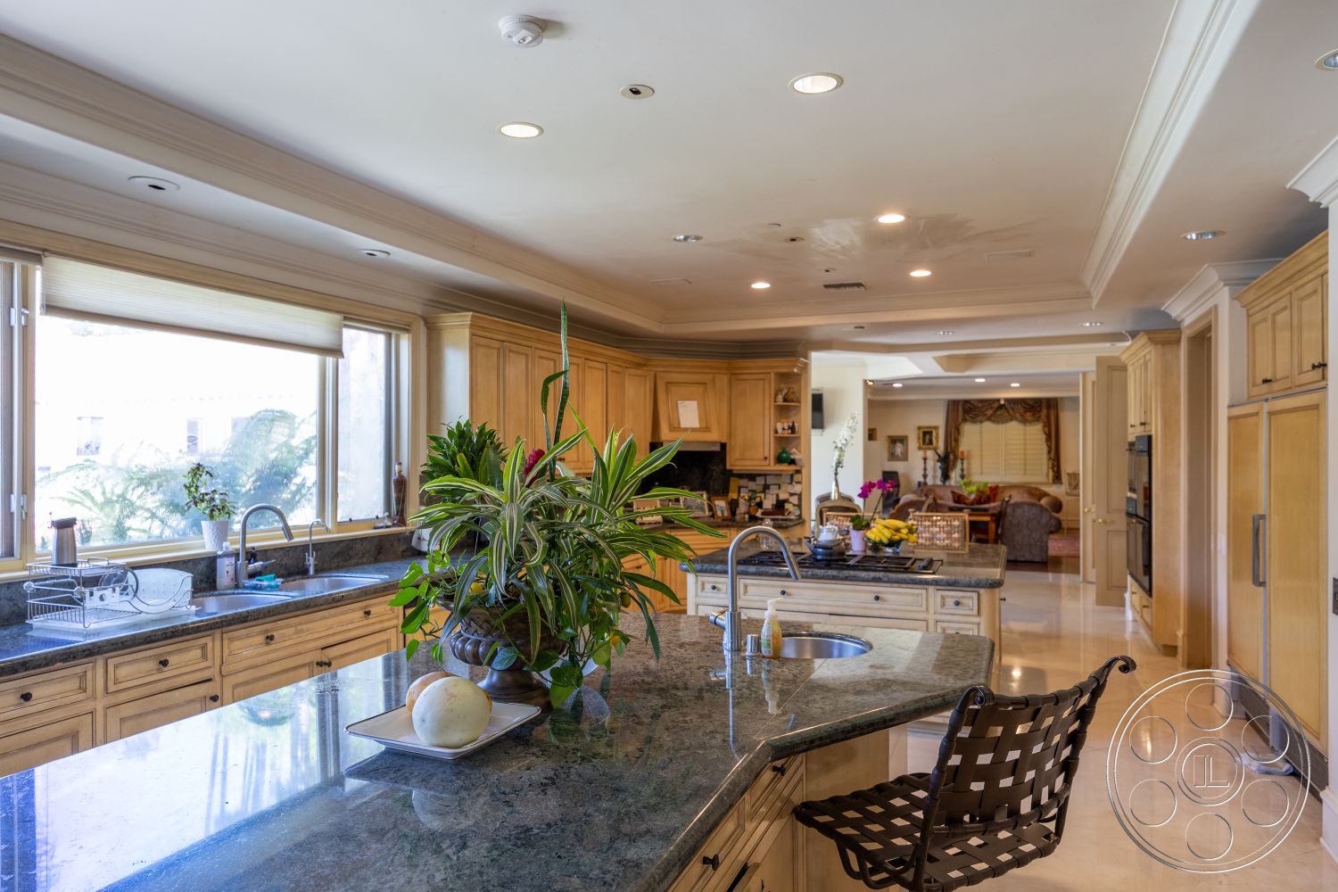 Medit 165 - neutral color palette, tile flooring, floor-to-ceiling windows, bright interior, textured plaster walls, oak cabinetry, recessed ceiling lights, elegant crown molding, rectangular kitchen island, open-concept kitchen layout, granite kitchen countertops, plant accent decor, stainless steel double sink, brushed nickel faucet, modern barstools, sunny kitchen with natural light, dining area connection, cozy family room adjacent, spacious kitchen storage, well-lit work surfaces