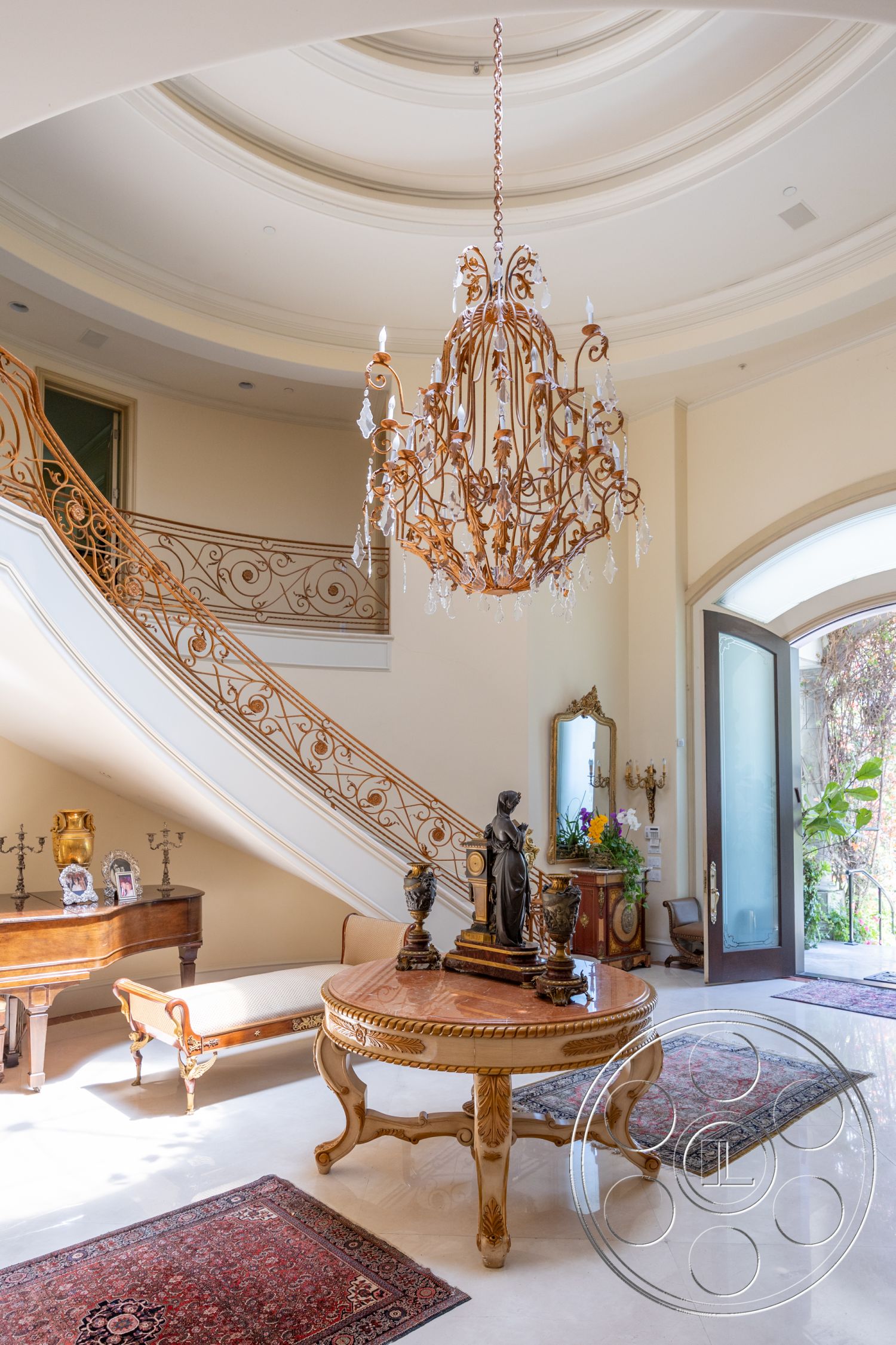 Medit 165 - interior chandelier,, orate wrought iron railing,, curved staircase,, polished marble foyer floors,, round wooden coffee table,, intricate ceiling moldings,, classic wooden entry door,, detailed wood paneling,, luxurious rugs,, elegant statue decor,, stylish accent chairs,, vibrant plant arrangement,, traditional wall sconces,, expansive foyer space,, grand entryway design