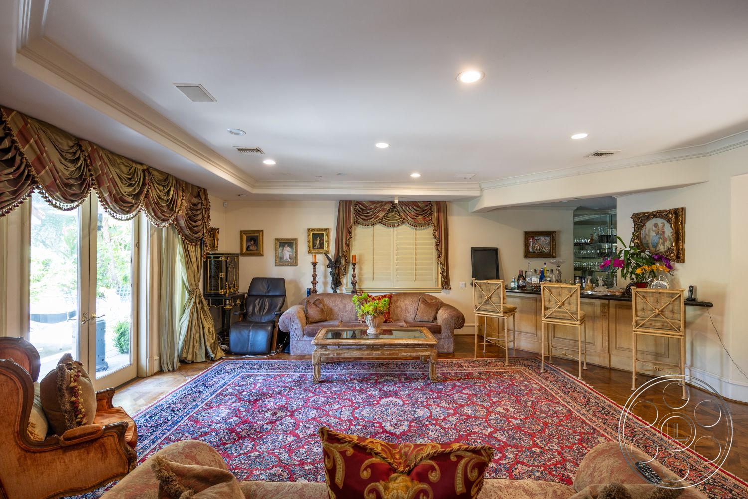 Medit 165 - hardwood flooring, cozy reading nook, glass patio doors, recessed ceiling lights, interior living room, decorative table with floral arrangement, framed artwork on walls, traditional Persian area rug, cream-colored painted walls, exposed crown molding, luxurious drapery with tassels, bar area with wooden cabinetry, upholstered sofa with ornate detailing, traditional accent chairs, window treatments with elegant patterns