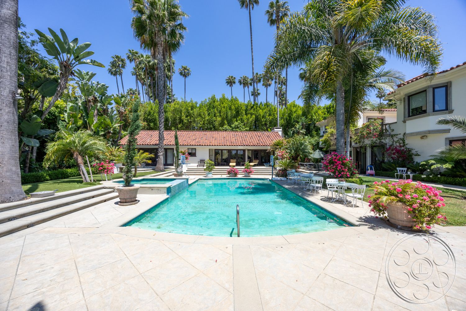 Medit 165 - outdoor seating area, floor-to-ceiling windows, green lawn, tropical landscaping, terracotta roof tiles, concrete pool deck, arched entrance, rectangular pool, wooden outdoor furniture, stucco exterior walls, concrete pool coping, exterior pool area, potted flowering plants, tile patio flooring, palm trees surrounding pool, brick walkway steps, sloped garden beds, home office view, sunny backyard setting, garden patio area