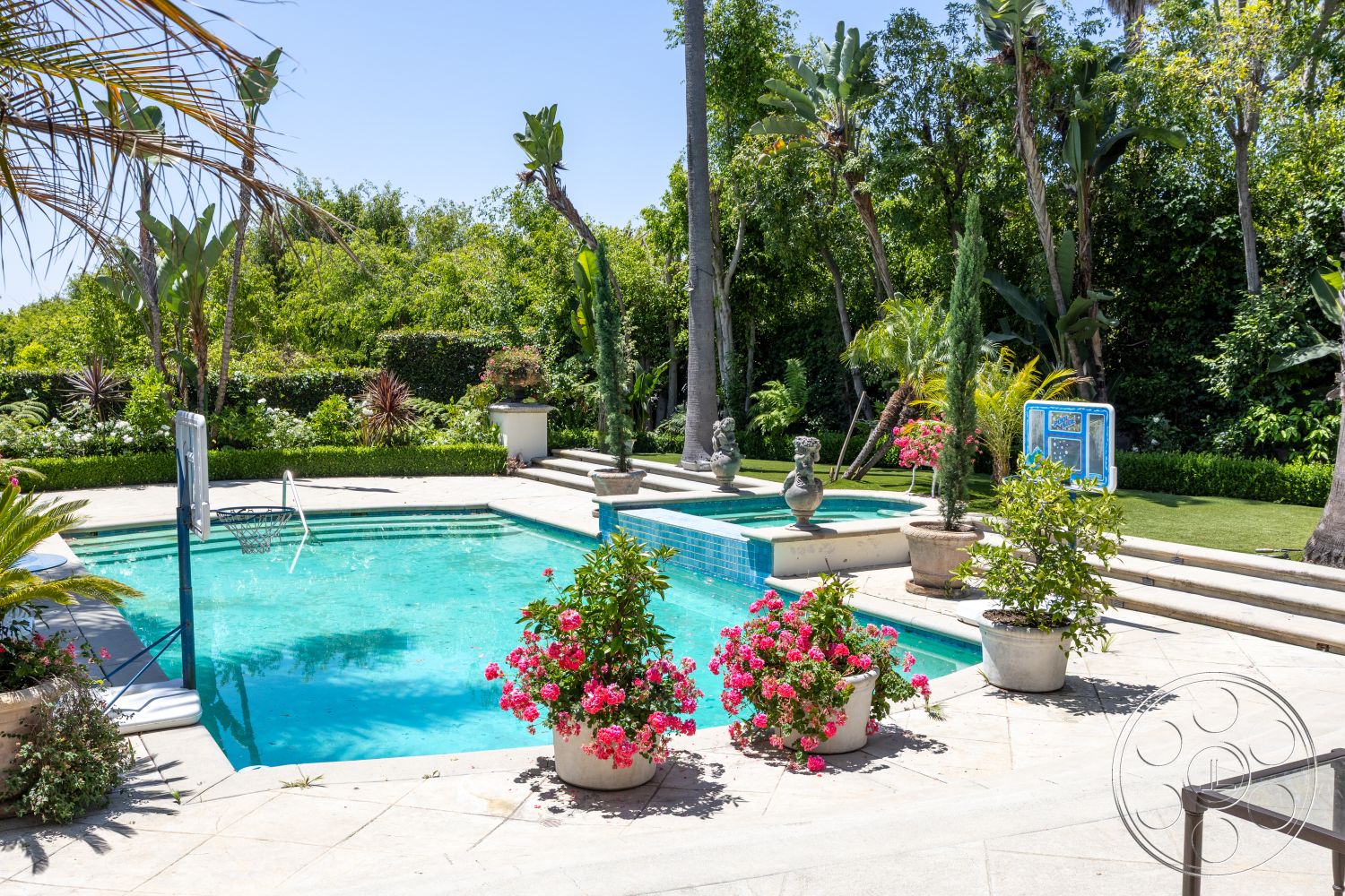 Medit 165 - outdoor relaxation area, rectangular pool, steps leading to pool, exterior concrete pool border, concrete patio flooring, landscaped garden setting, sunny outdoor environment, tropical plant landscaping, blue mosaic tile accents, ornamental stone planters, potted floral arrangements, suburban backyard oasis, lush greenery background