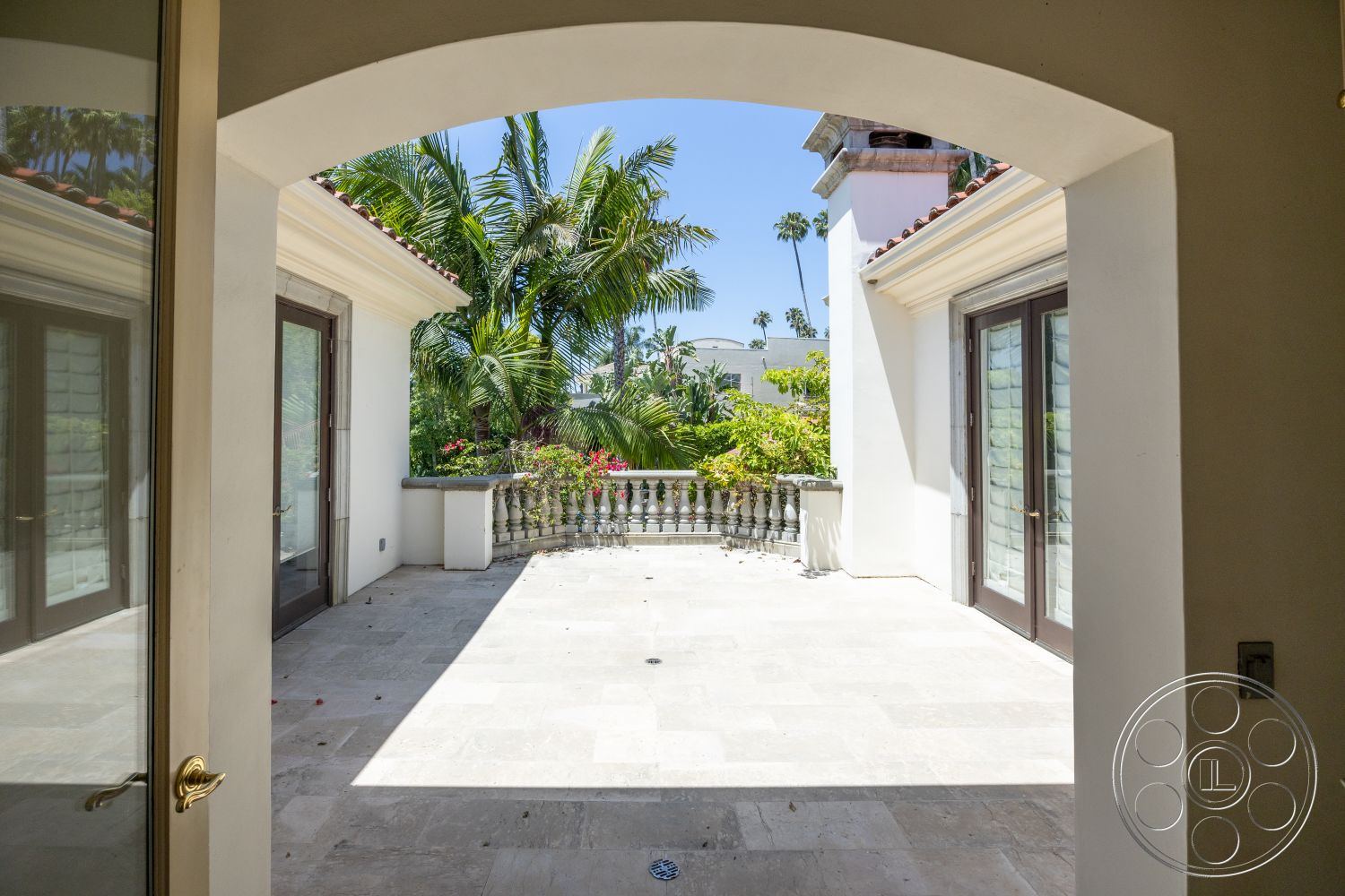 Medit 165 - white stucco walls, low-maintenance plants, open-air design, arched doorways, Mediterranean architectural style, outdoor garden view, palm tree landscaping, double glass doors, exterior patio space, travertine stone flooring, ornamental balcony railing, sunlight-filled area, horizontal decorative wood trim, private courtyard setting