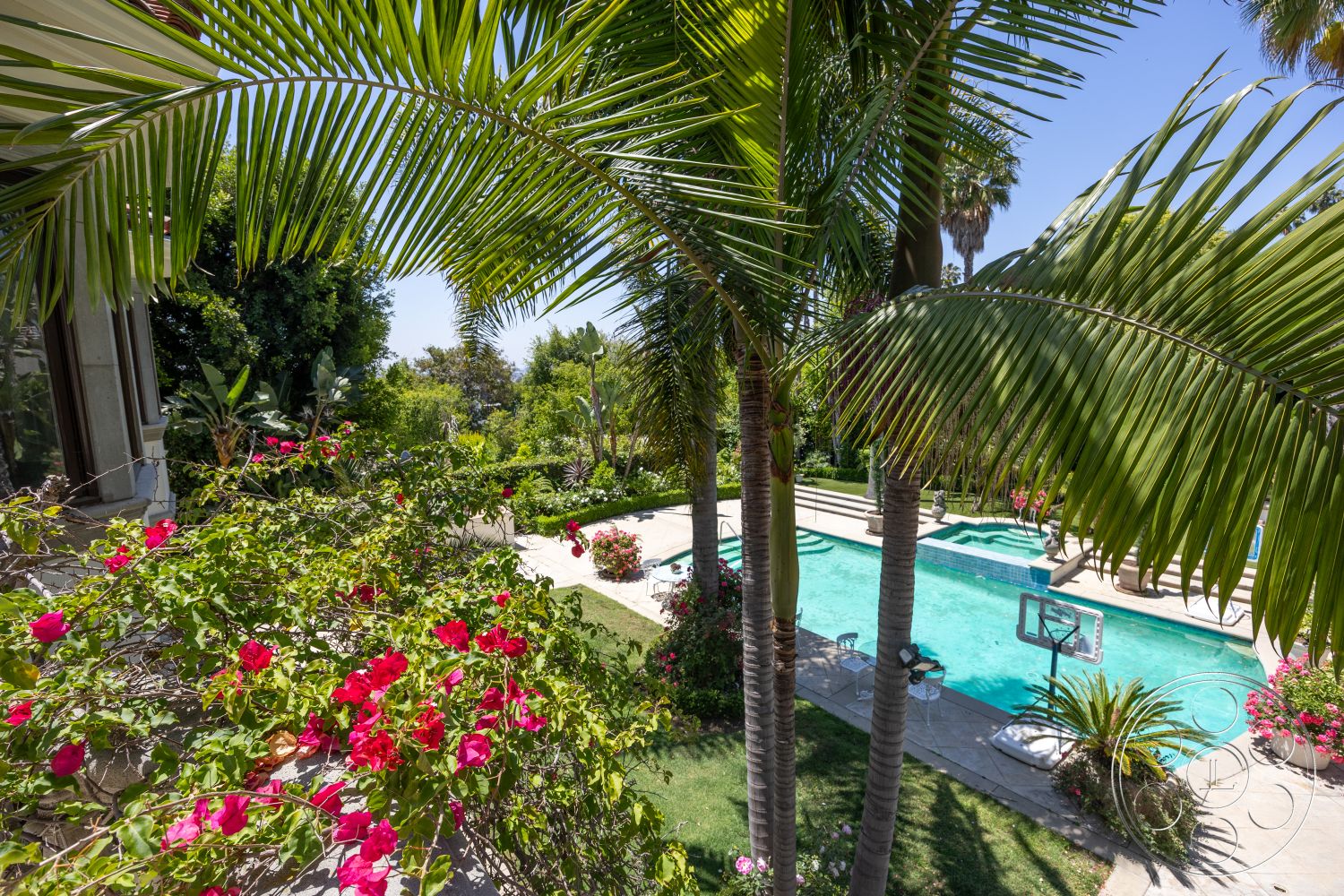 Medit 165 - clear blue water, inviting outdoor space, tropical palm trees, concrete pool deck, well-maintained garden, open-air setting, brick garden wall, exterior landscaped garden, sunny outdoor environment, pool area with rectangular pool, flowering bougainvillea shrubs, patio seating with chairs, stone pool border, lush greenery surrounding the pool, hardscape pathways, urban backyard retreat