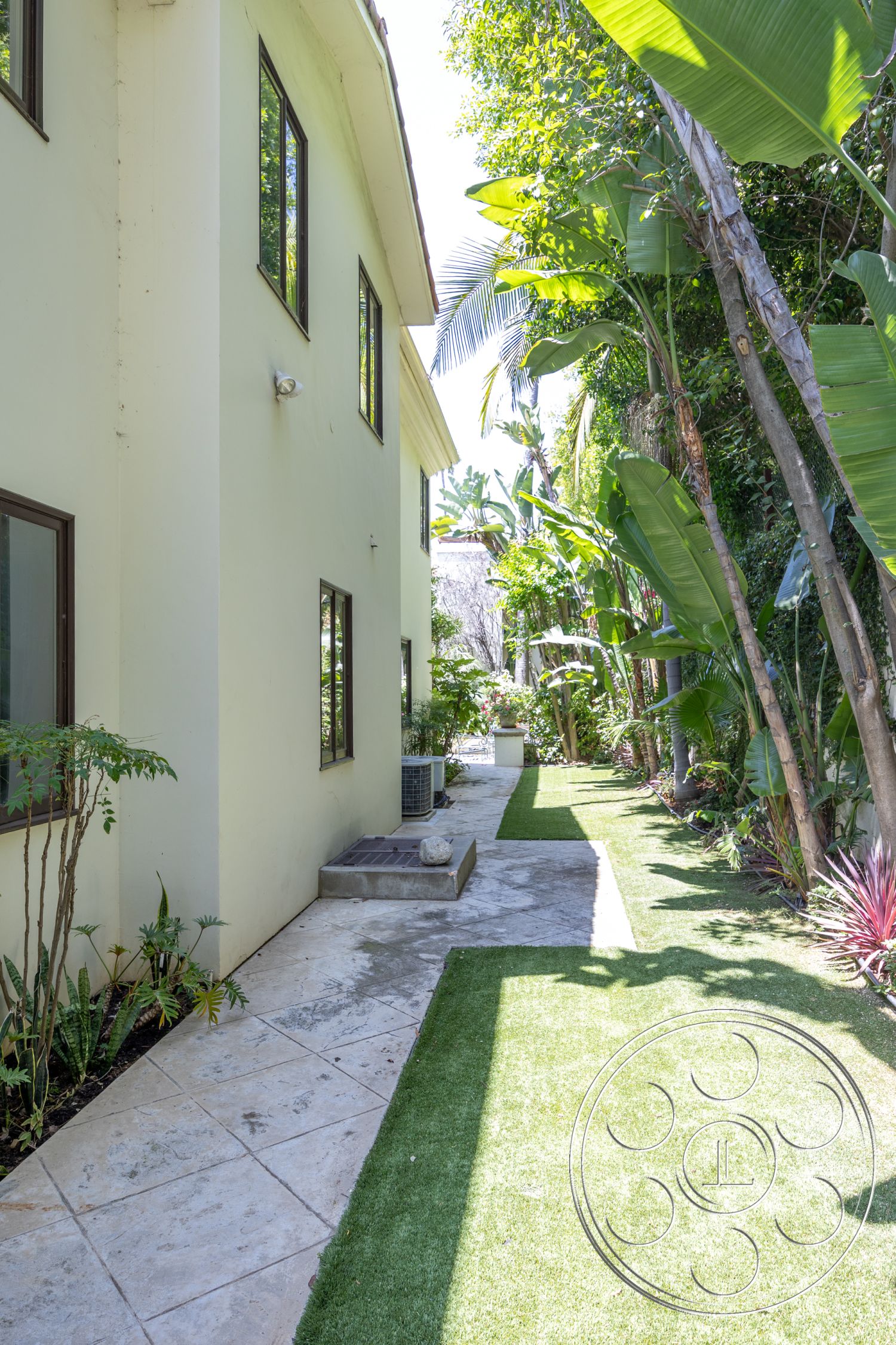 Medit 165 - natural stone accents, palm trees, concrete steps, contemporary architecture, slate stone pathway, green grass lawn, backyard retreat, modern home design, stucco exterior walls, large rectangular windows, landscaped tropical garden, paved garden path, aloe vera plants, yellow painted walls, exterior lighting fixture, textured plaster finish, lush plant foliage, urban tropical setting, accessible side garden