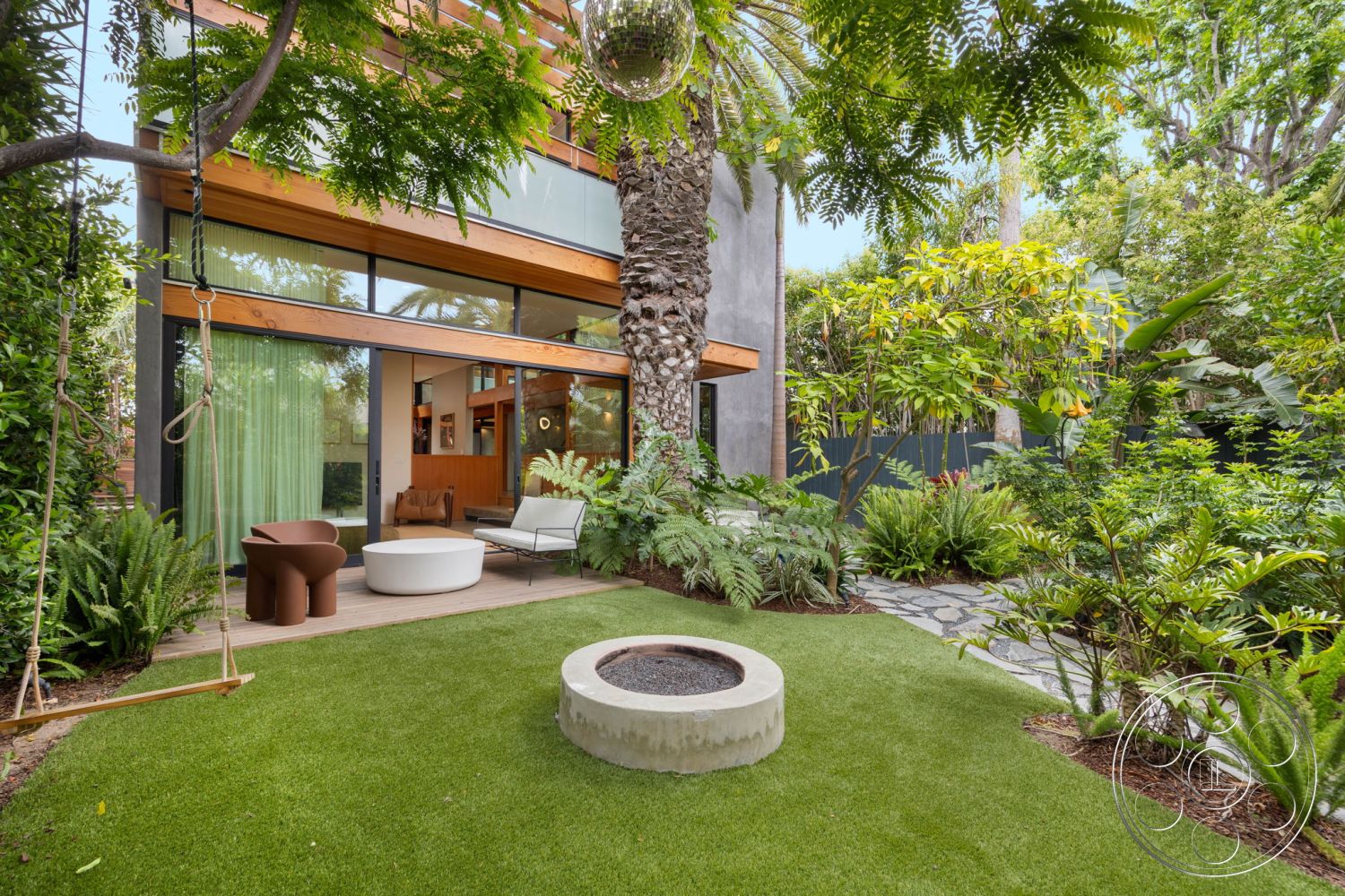Modern 508 - exterior, lush greenery, modern outdoor furniture, grass lawn, wood deck, textured stone pathway, exposed wood ceiling beams, minimalist garden design, floor-to-ceiling glass windows, concrete fire pit, palm tree landscaping, curved patio, swinging chair