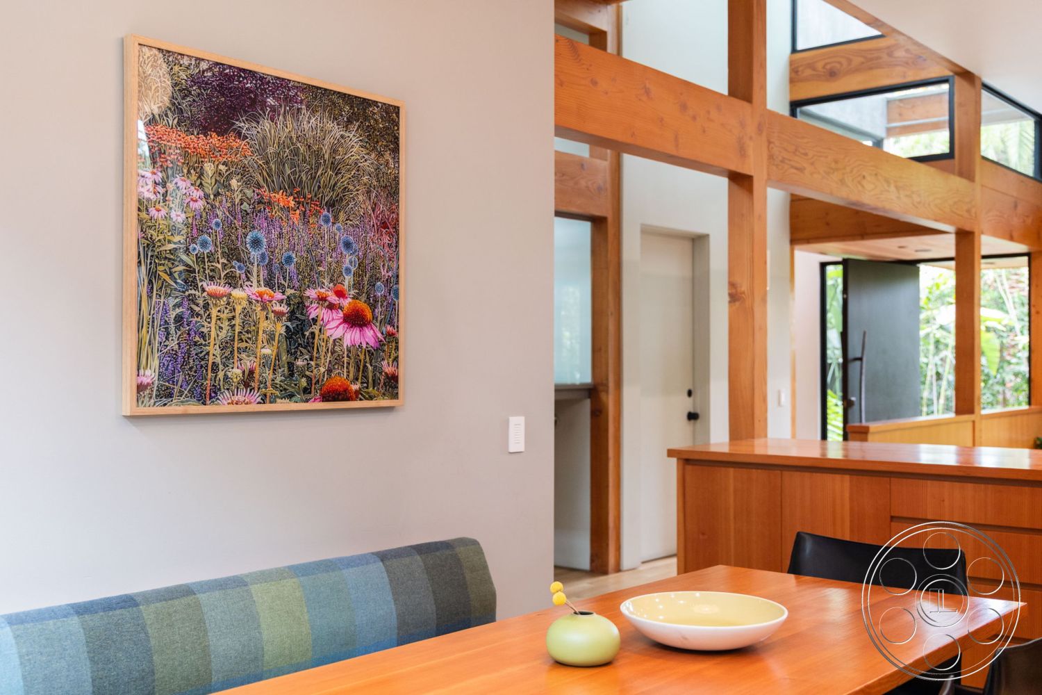 Modern 508 - natural light, open floor plan, natural wood cabinetry, spacious living area, mid-century modern style, exposed wood ceiling beams, modern architectural details, hardwood dining room floors, bright indoor plants, interior wooden beam ceiling, light gray painted walls, minimalist dining table, framed floral artwork, green plaid upholstered bench, floating kitchen cabinets, black dining chair, decorative porcelain bowl, large window openings