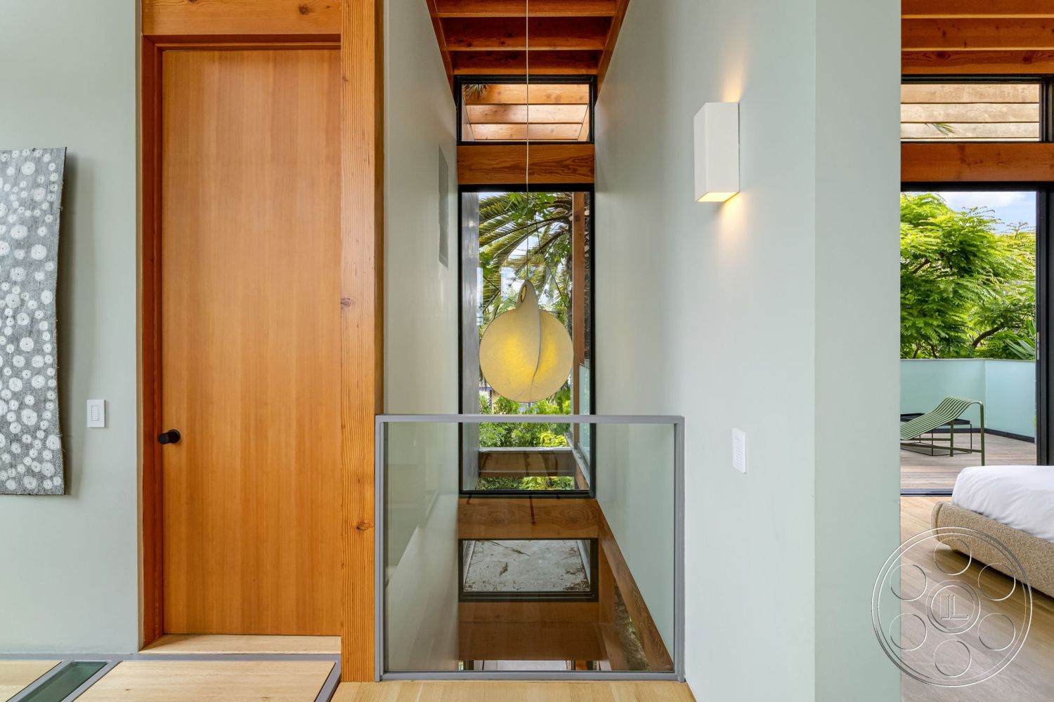Modern 508 - indoor-outdoor flow, large sliding glass doors, contemporary architectural style, exposed wood ceiling beams, minimalist pendant lighting, glass balcony railing, palm tree outdoor view, textured plaster interior walls, wooden entrance door, concrete floor base, natural light-filled foyer, softwood flooring, modern art wall fixture, bright open interior space
