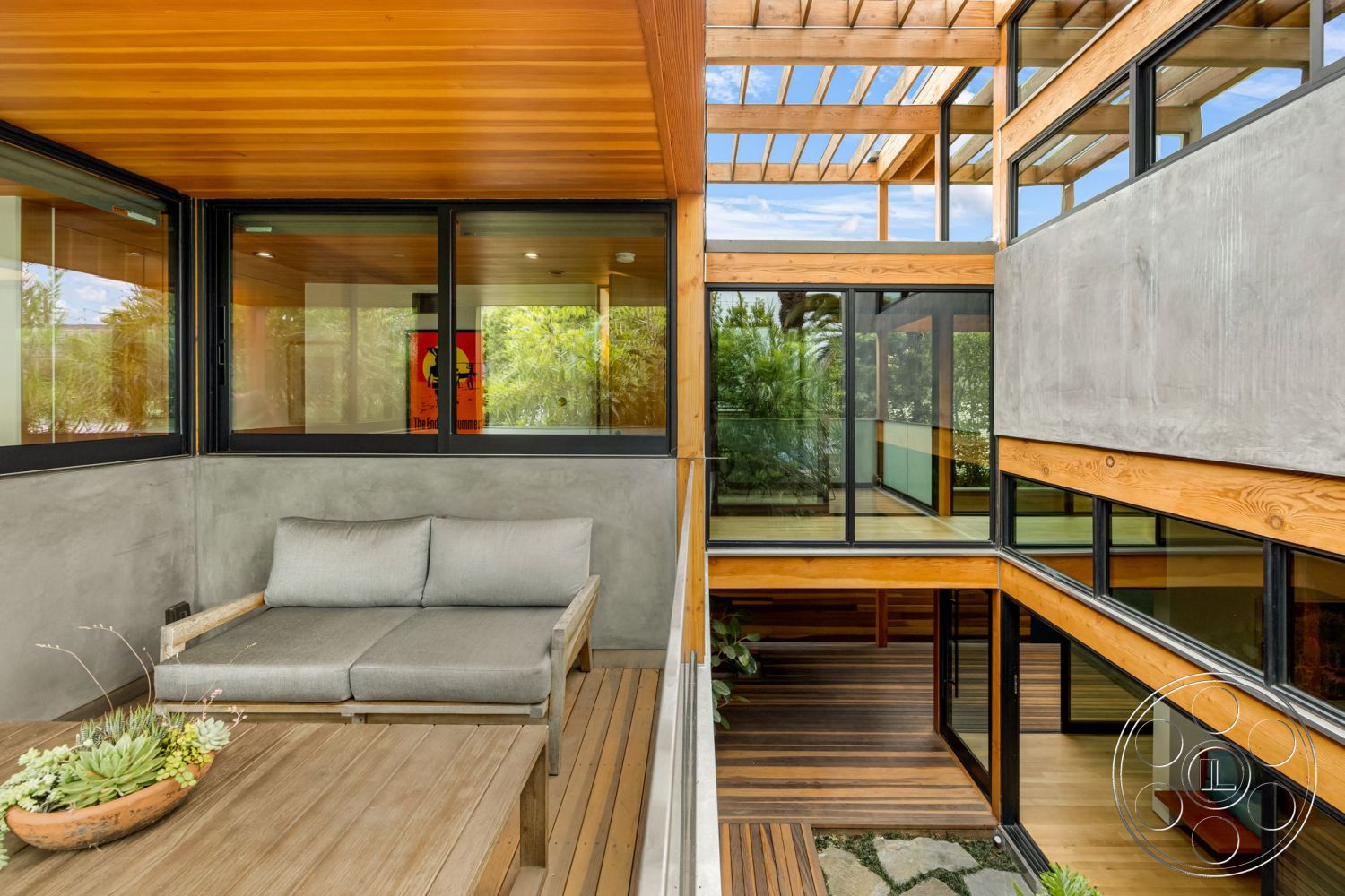Modern 508 - wood beam ceiling in exterior seating area, concrete wall in modern courtyard, glass window frames with panoramic views, sliding glass doors leading to outdoor space, wooden deck flooring in outdoor lounge, stone landscaping features around seating area, stucco wall elements in architectural design, exposed wood paneling in interior living space, minimalist outdoor furniture cushions, natural light flooding interior spaces through large windows, modern outdoor table with decorative succulents, open floor plan connecting indoor and outdoor living areas, architecturally framed views of surrounding greenery, interior courtyard with lush plant integration, modern aesthetic with a focus on natural materials
