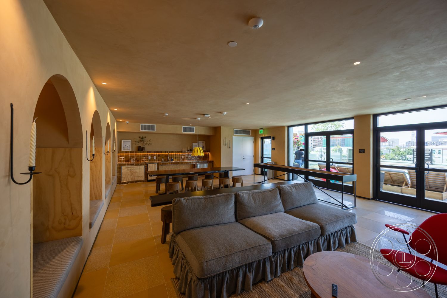 Apartment 55 - natural lighting, inviting atmosphere, open concept layout, modern pendant lighting, glass sliding doors, textured wall finish, floor-to-ceiling windows, urban aesthetic, casual living space, arched openings, spacious interior, contemporary furniture design, upholstered sectional sofa, minimalist dining table, interior plaster walls, interior tile flooring, wooden bar countertop, decorative tile kitchen backsplash, built-in seating nooks, wooden accent beams