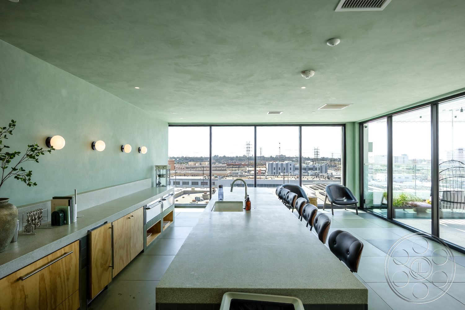 Apartment 55 - interior floor-to-ceiling windows, interior round dining table, interior panoramic city skyline view, interior concrete kitchen countertop, interior custom wood cabinets, interior green plaster wall, interior tile kitchen flooring, interior mid-century modern design, interior linear light fixtures, interior angular kitchen layout, interior open-plan living space, interior contemporary bar stools