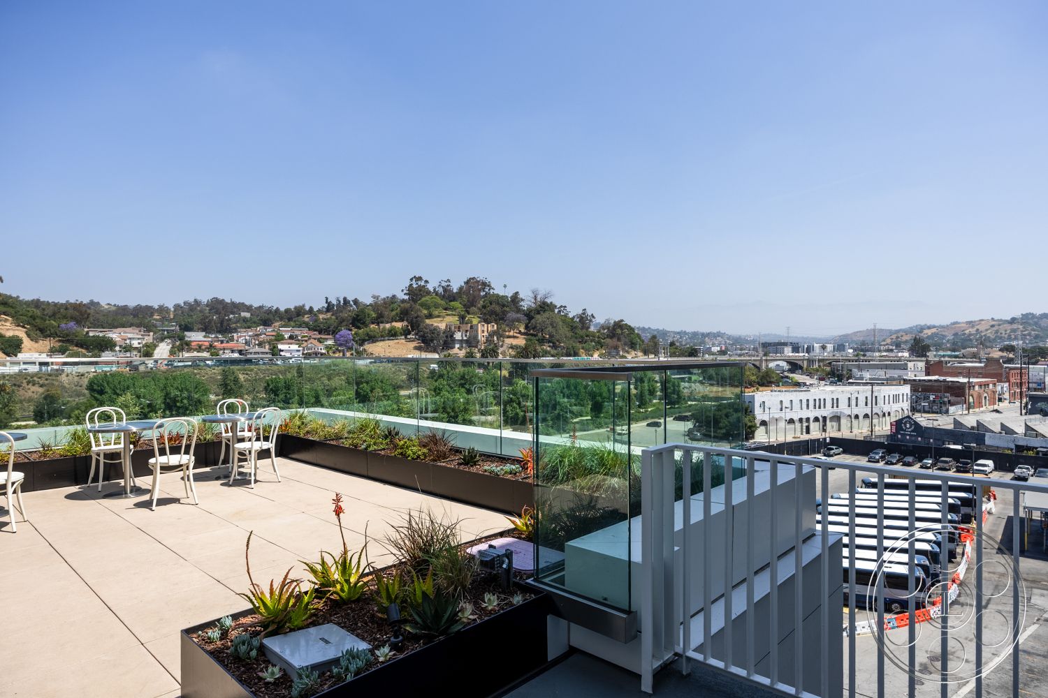 Apartment 55 - glass railing, landscaped surroundings, surrounding hillside, concrete planters, modern architectural style, urban skyline view, sunny outdoor space, flat roof design, concrete patio flooring, minimalist outdoor furniture, steel structural elements, open air environment, exterior terrace, large planters with succulents, elevated outdoor seating area, urban rooftop terrace, greenery-enhanced exterior