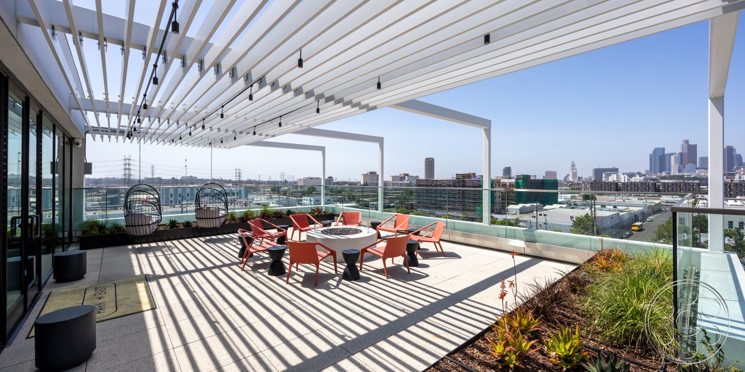 Apartment 55 - glass railing, modern outdoor furniture, urban rooftop, city skyline view, ceramic planters, open-air seating area, landscaped garden area, concrete patio floor, exterior terrace, metal pergola structure, sunshade design, hanging swing chairs, striped shadow patterns, stainless steel furniture accents