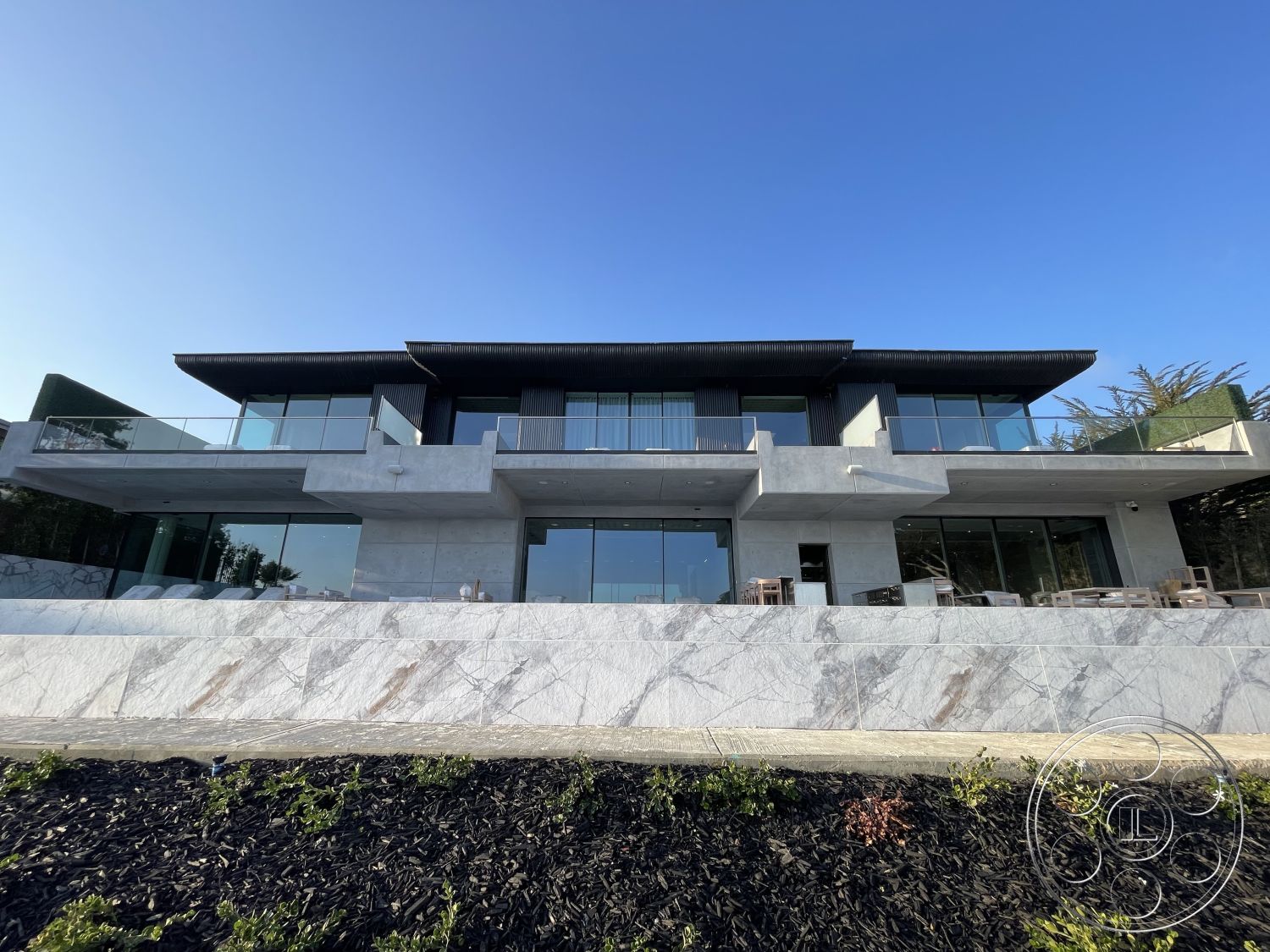 Modern 509 - glass sliding doors, modern architectural style, city skyline view, hillside location, open plan layout, floor-to-ceiling glass windows, exterior concrete walls, concrete patio area, minimalist exterior design, exterior marble stone facade, steel balcony railings, exposed wood roof overhang, landscape garden with black mulch, curved terrace, horizontal wood siding accents