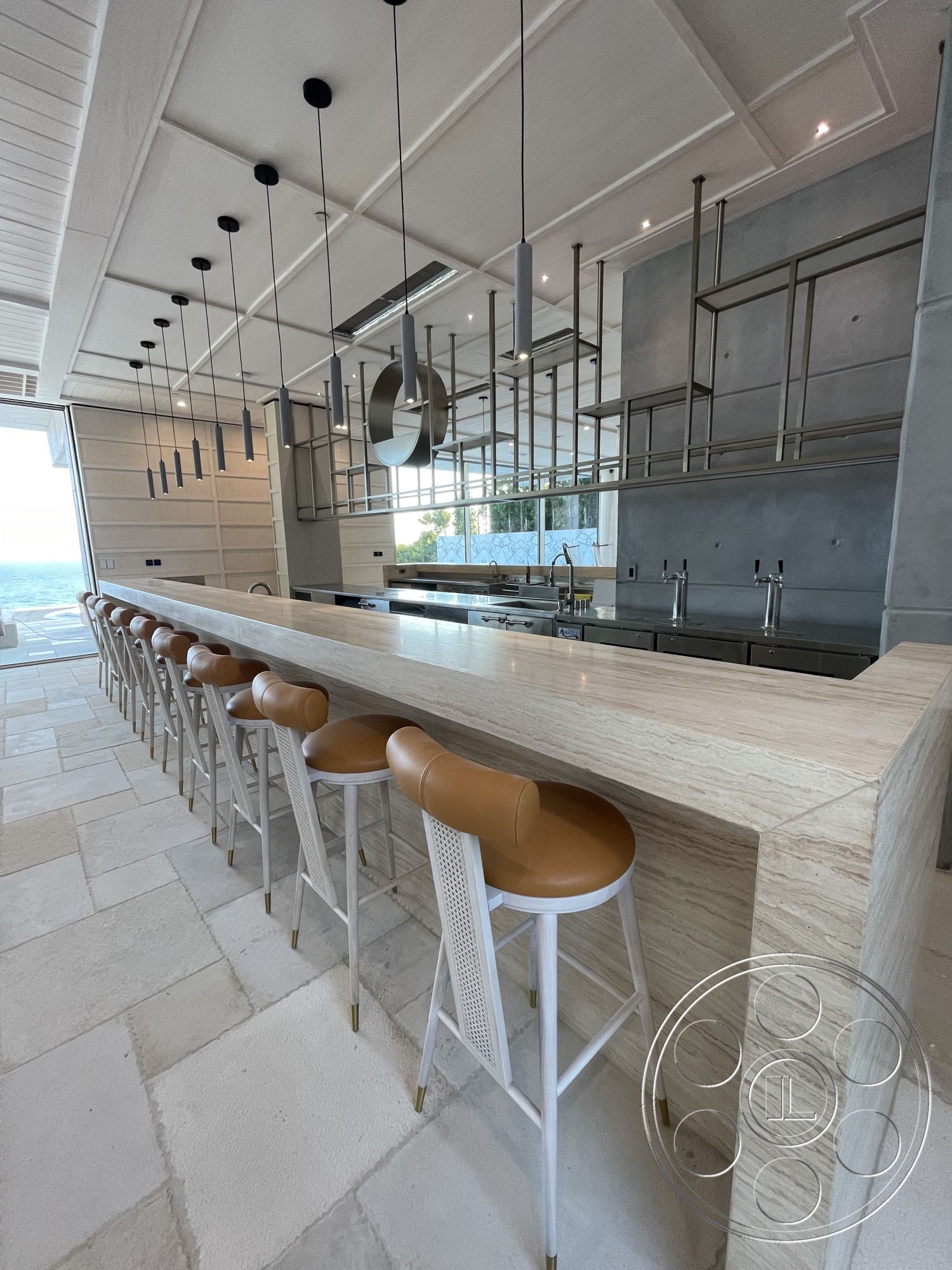 Modern 509 - interior exposed wood ceiling beams, interior warm neutral color palette, interior contemporary lighting fixtures, interior marble kitchen bar countertop, interior stone tile flooring, interior stainless steel kitchen fixtures, interior modern bar stools with leather seats, interior open concept kitchen design, interior wall paneling with textured finish, interior large panoramic windows with ocean view, interior minimalistic kitchen shelving, interior seamless connection to outdoor space