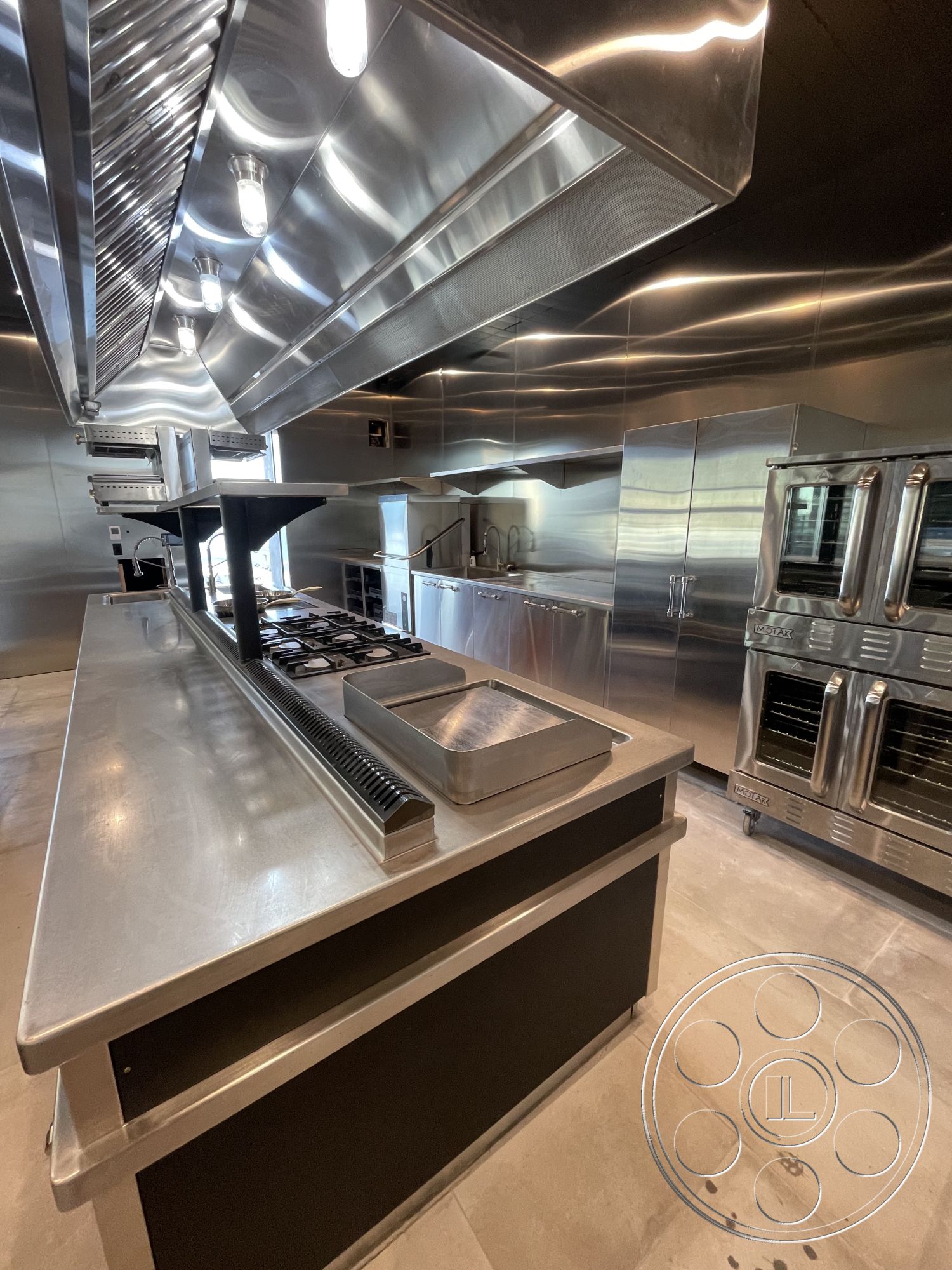 Modern 509 - concrete flooring, exposed ductwork, under-cabinet lighting, stainless steel kitchen appliances, rectangular kitchen island, minimalist kitchen design, glass window walls, open concept kitchen layout, floor-to-ceiling cabinetry, stainless steel countertops, stainless steel wall cabinets, stainless steel exhaust hood, modern industrial kitchen design, commercial-grade kitchen setup, task lighting above kitchen island, kitchen prep area
