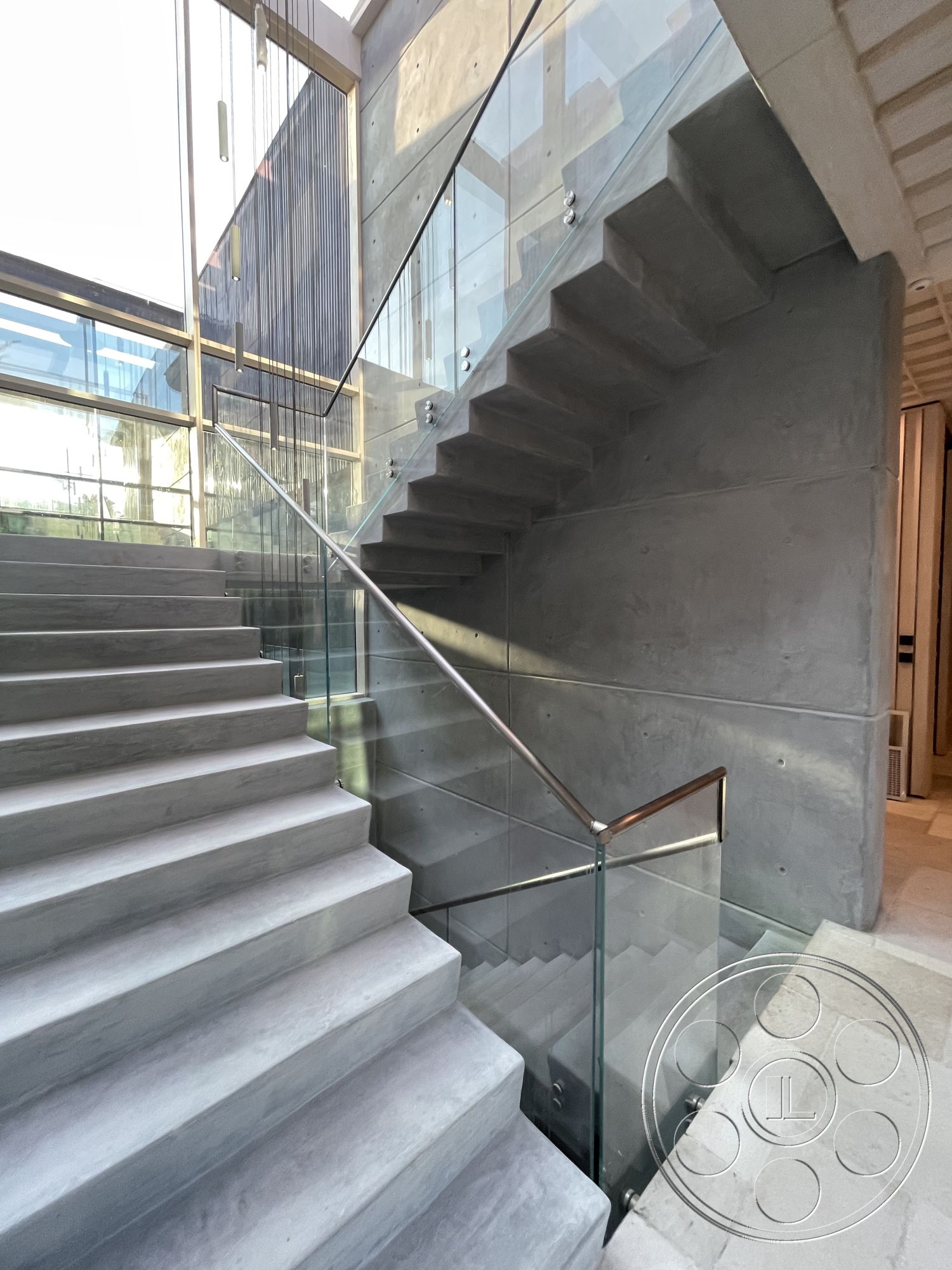 Modern 509 - light-filled interior space, contemporary architectural details, textured concrete wall panels, glass railing with stainless steel handrail, modern industrial style, interior concrete stair treads, exposed concrete wall finish, natural light from large glass windows, smooth polished concrete floor, minimalist modern design elements, open staircase with cantilevered steps, elegant stairway design, architectural glass elements, transitional space between floors
