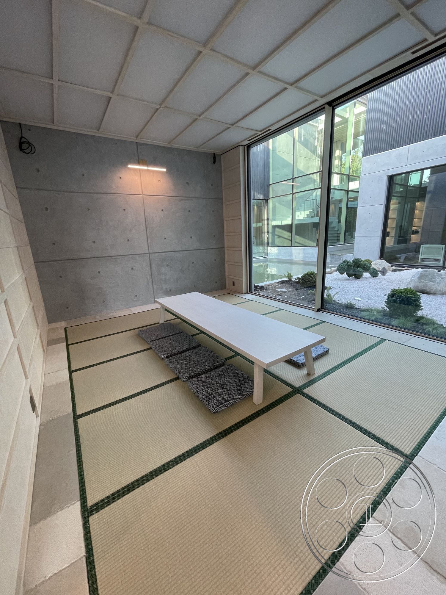 Modern 509 - neutral color palette, open floor plan, exposed concrete walls, modern architectural style, contemporary interior, natural light-filled space, floor-to-ceiling glass windows, concrete ceiling beams, tatami mat flooring, minimalist wooden dining table, garden courtyard view, white cushion seating, textured concrete surfaces, green accent details, Japanese inspired design