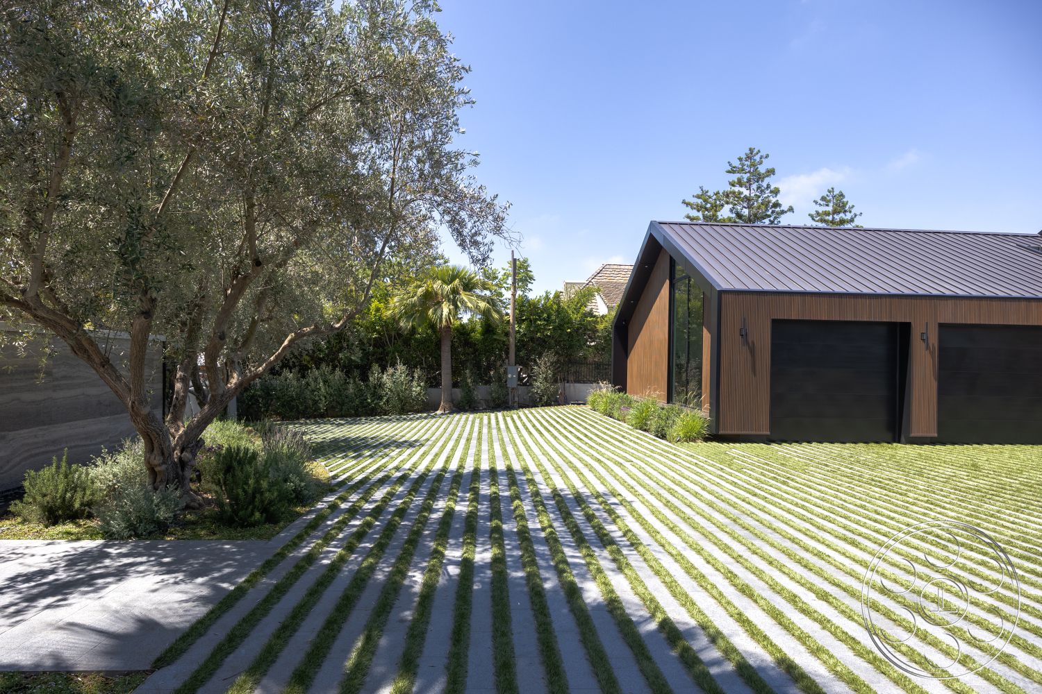 Modern 510 - exterior, open space layout, floor-to-ceiling windows, concrete walkway, minimalist architecture, integrated landscaping, designed for sunlight, sloped metal roof, patterned grass landscaping, wood panel siding, modern garage design, contemporary home style, striped lawn design, natural greenery surrounds, outdoor tree canopy, modern residential exterior