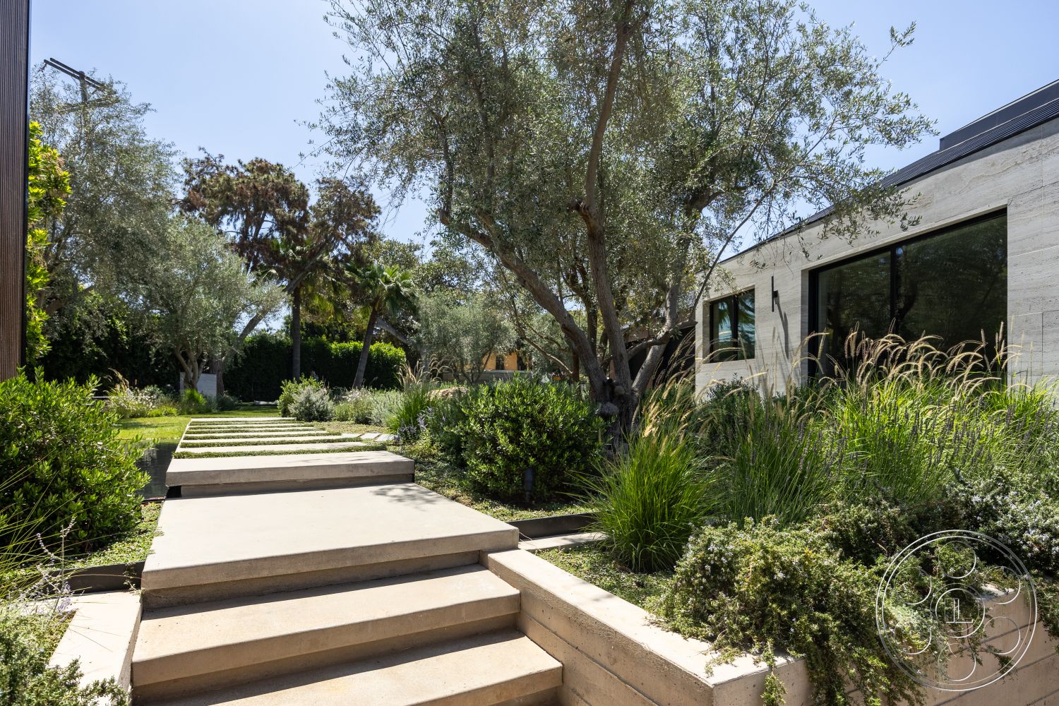 Modern 510 - exterior, natural stone accents, textured concrete walls, tropical plants, modern landscaping, low-maintenance garden, floor-to-ceiling windows, concrete stepping stones, contemporary architectural style, rectangular concrete walkway, olives trees, minimalist home design, open sight lines, green garden borders