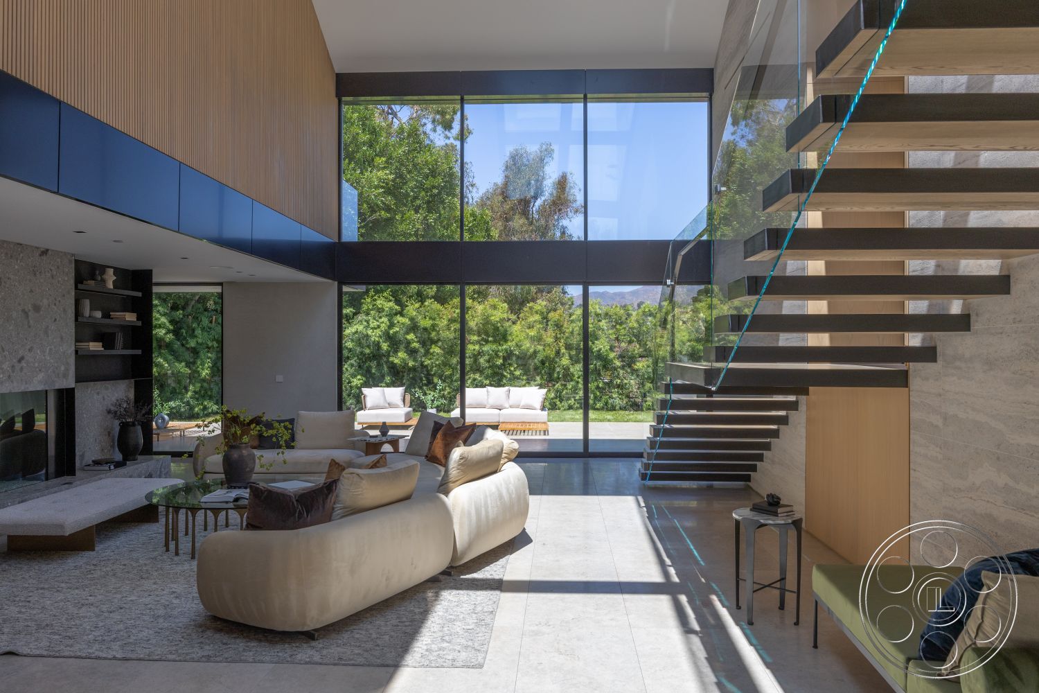 Modern 510 - neutral color palette, modern architectural style, large floor-to-ceiling windows, stylish accent pillows, modern seating area, exposed wood ceiling beams, textured plaster wall treatment, minimalist furniture arrangement, open-concept interior layout, concrete living room floor, glass panel staircase with floating steps, outdoor patio area visible, surrounding green landscape view, slate stone fireplace surround, elegant coffee table design, high ceilings with natural light, wood accent wall above fireplace, private garden space outside, stylish contemporary decor, interior greenery accents