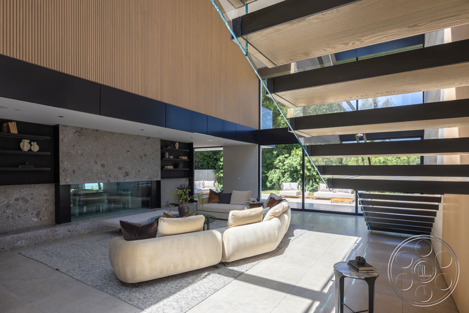 Modern 510 - neutral color palette, polished concrete flooring, large floor-to-ceiling windows, light wood paneling, soft gray area rug, open-concept layout, minimalist furniture design, natural light emphasis, exposed stone feature wall, interior modern living room, floating wooden staircase, glass railing details, black steel stair supports, contemporary fireplace design, spacious indoor-outdoor flow