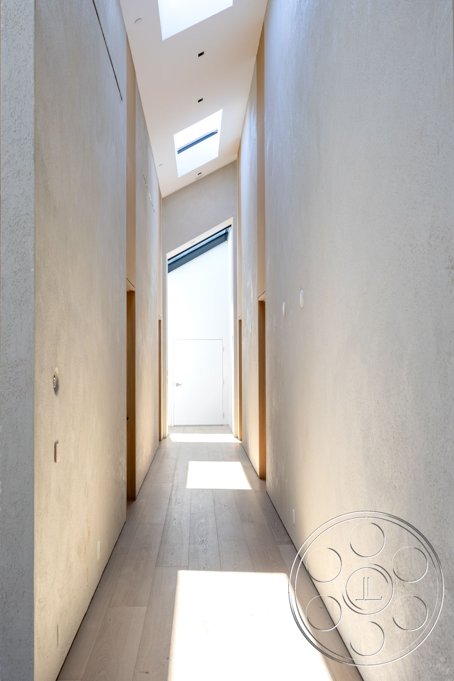 Modern 510 - neutral color palette, light hardwood flooring, narrow corridor, textured plaster walls, interior hallway, modern minimalist design, skylights for natural lighting, natural wood trim details, flush white doors, high ceiling with linear light fixtures, functional architectural layout