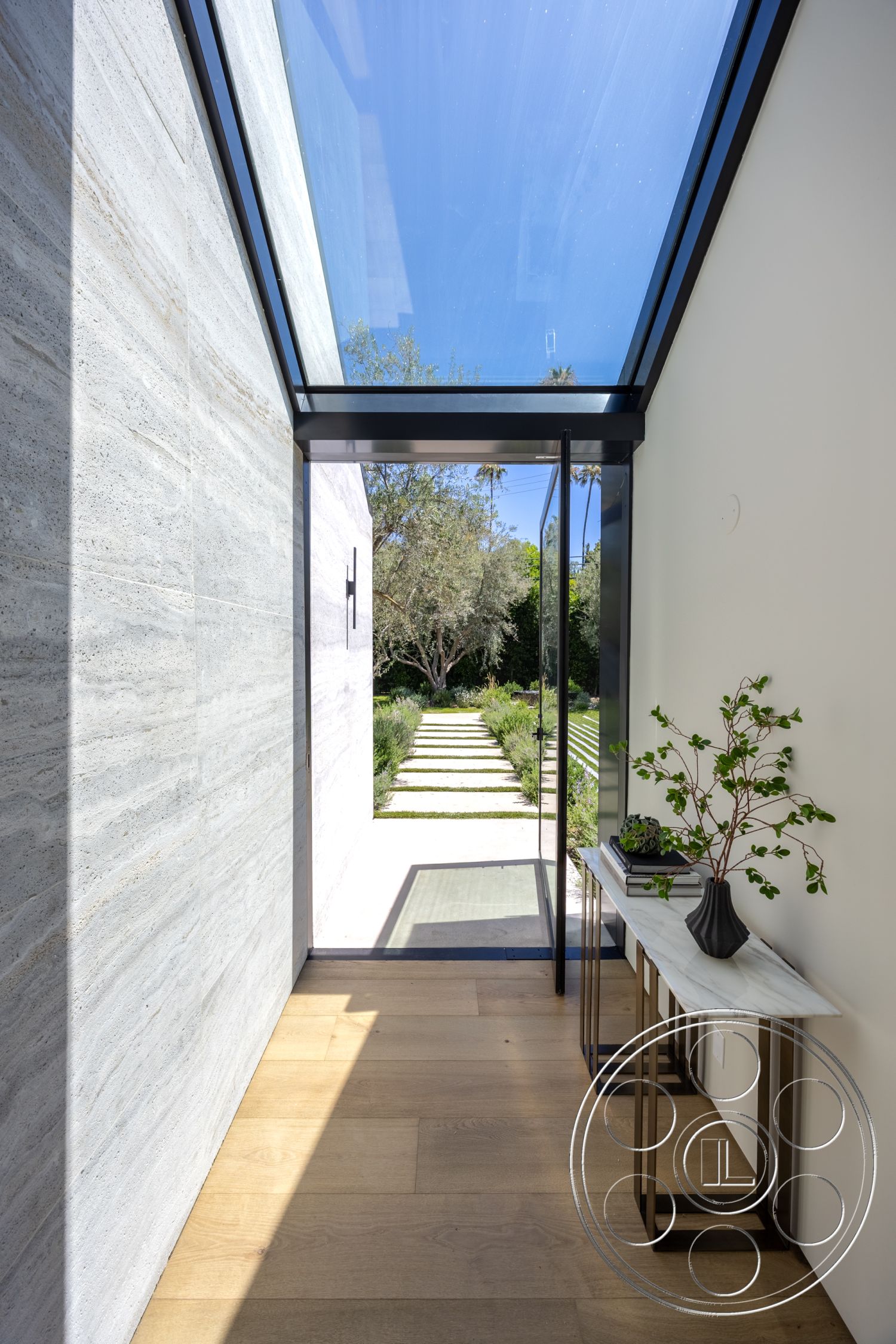 Modern 510 - contemporary style, natural wood flooring, greenery view, horizontal lines, landscape view, exposed concrete walls, bright natural lighting, open hallway, interior hallway, modern architectural design, metal table legs, smooth plaster walls, minimalist interior, glass overhead skylight, marble entry console table, pathway leading to garden, straight pathway, crisp architectural details, wooden accent features