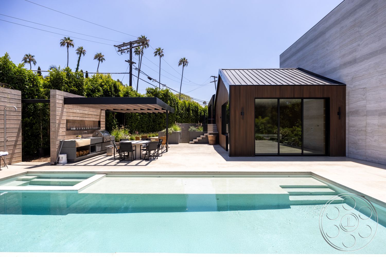 Modern 510 - low-maintenance landscaping, minimalist design, glass sliding doors, city skyline view, rectangular pool, wood beam pergola, exposed aggregate concrete, concrete pool border, interior glass partition walls, landscape with palm trees, tile patio flooring, urban oasis setting, outdoor kitchen with stainless steel appliances, exterior wood slat wall, modern bungalow style, hardscape outdoor living area, contemporary residential architecture, extensive natural lighting