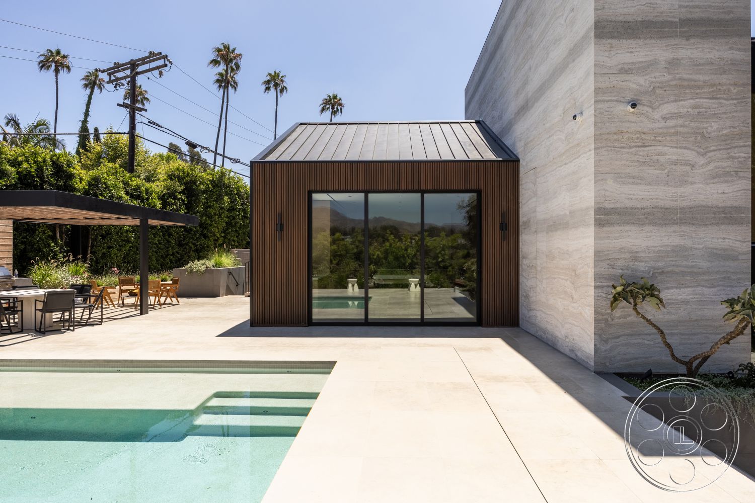 Modern 510 - textured stone wall, glass sliding doors, rectangular swimming pool, outdoor dining area, concrete planters, transparent glass railing, metal roof, wooden dining chairs, concrete patio flooring, landscaped garden setting, minimalist architectural style, exterior concrete pool deck, modern flat roof, wood slatted pergola, urban backyard environment