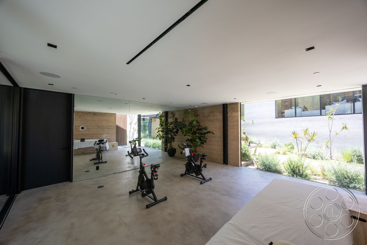 Modern 510 - home gym, neutral color palette, polished concrete flooring, modern lighting fixtures, floor-to-ceiling windows, contemporary architectural style, minimalist interior design, potted indoor plants, outdoor garden view, natural light filled space, exposed wood panel walls, mirrored wall treatment, black metal framing, open floor plan fitness room