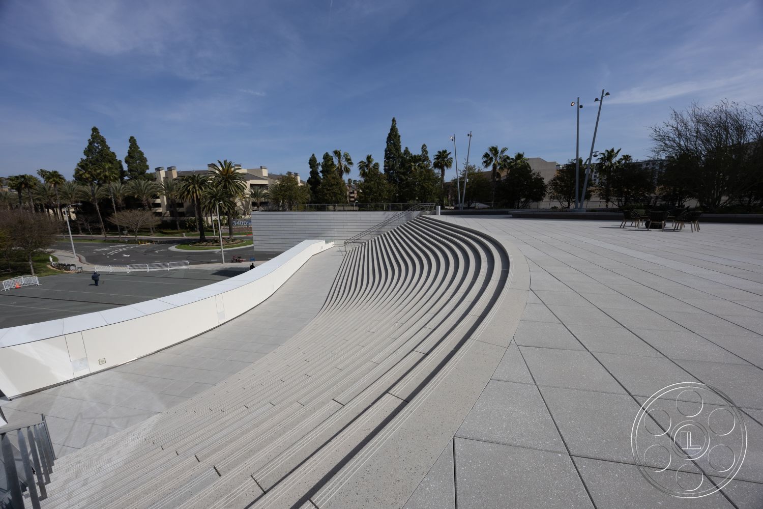 Museum 4 - smooth concrete flooring, textured concrete surface, modern architectural details, curved concrete steps, exterior concrete amphitheater seating, landscaped with palm trees, urban public space design, step seating arrangement, modernist architectural features, configured for outdoor events, smooth lines in design, exposed surfaces, surrounding urban architecture, open-air gathering area, integrated seating elements