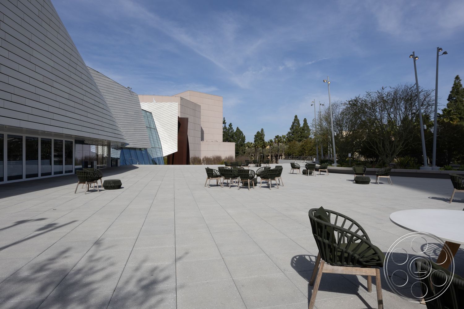 Museum 4 - exterior, low-maintenance landscaping, glass facade, open outdoor seating area, modern architectural design, gray concrete pavers, triangular shapes, steel planters, commercial courtyard space, planted greenery backdrop