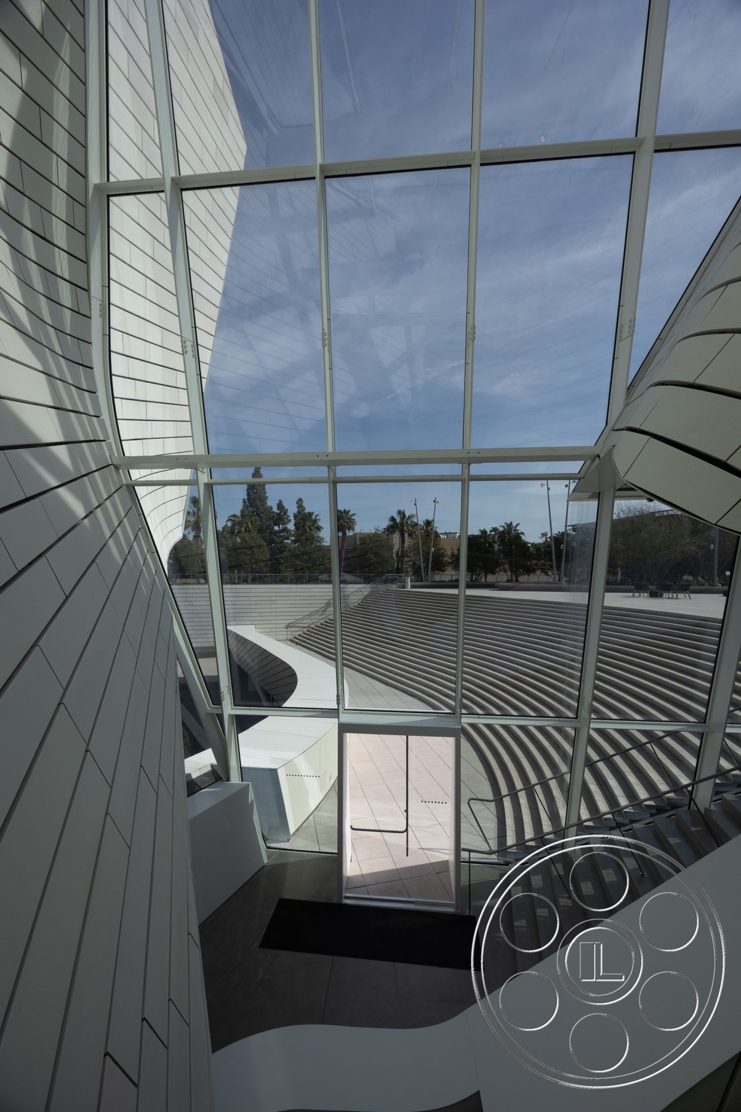 Museum 4 - natural light, ceramic tile flooring, spiral staircase, modern architectural style, exposed steel beams, curved walls, angular ceiling, open stair design, minimalist interior, glass wall structure, interior atrium, privacy glass entry door, concrete exterior steps, landscaped outdoor amphitheater, white panel cladding, interior foyer, urban landscape view
