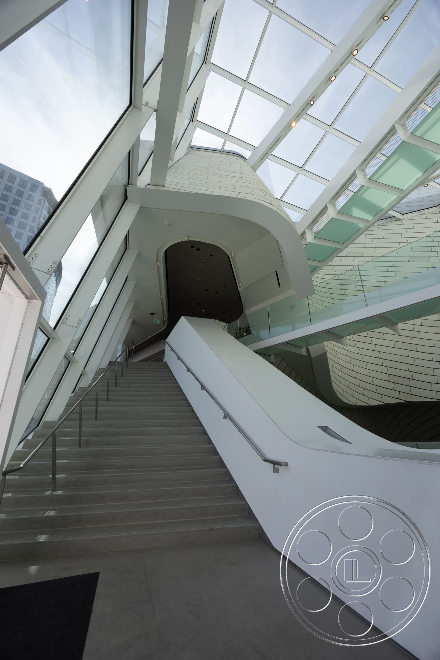 Museum 4 - modern design elements, exposed concrete walls, smooth concrete flooring, minimalist architectural style, open interior layout, exterior glass facade, high ceilings with skylights, steel railing details, floating stairs, interior concrete staircases, curved glass skylight, panelized white wall treatment, clean lines and angles, natural light infusing space