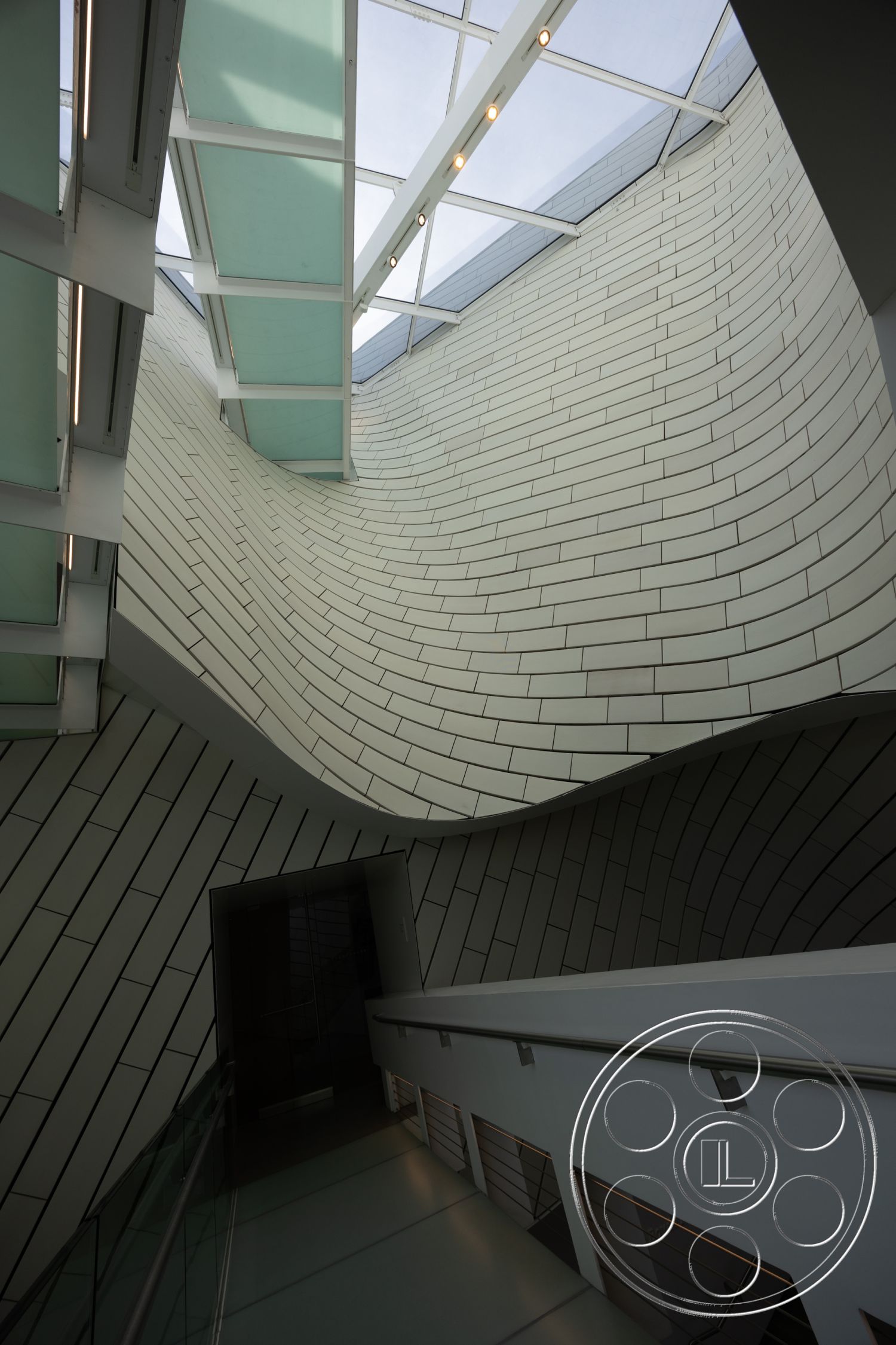 Museum 4 - smooth concrete flooring, textured wall surfaces, curved wall design, minimalist architectural style, natural light ambiance, open staircase design, interior ceramic wall tiles, glossy glass ceiling panels, steel railings with modern aesthetic, layered lighting fixtures, vertical tile arrangement, large skylight feature, bright modern interior, innovative structural design