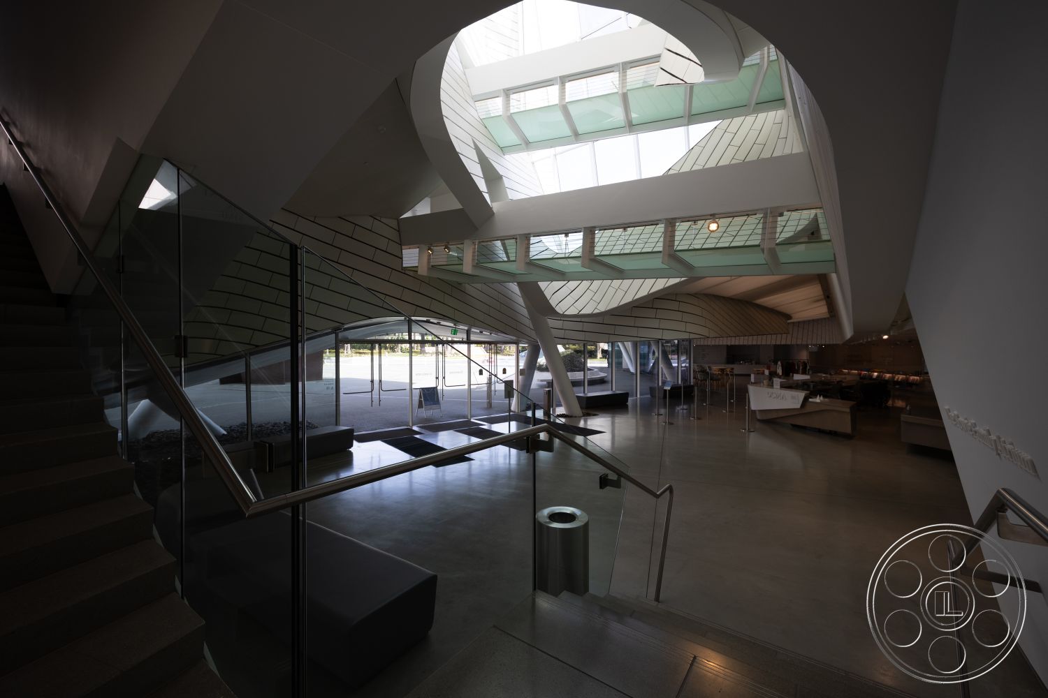 Museum 4 - open concept layout, large floor-to-ceiling windows, glass partition walls, minimalist architectural style, polished concrete finishes, soft seating areas, natural light-filled atrium, modern furniture design, interior concrete floors, exposed steel beam details, sculptural staircase design, angular ceiling shapes, modern metal railings, curvilinear rooflines, high ceiling interiors, industrial aesthetic elements
