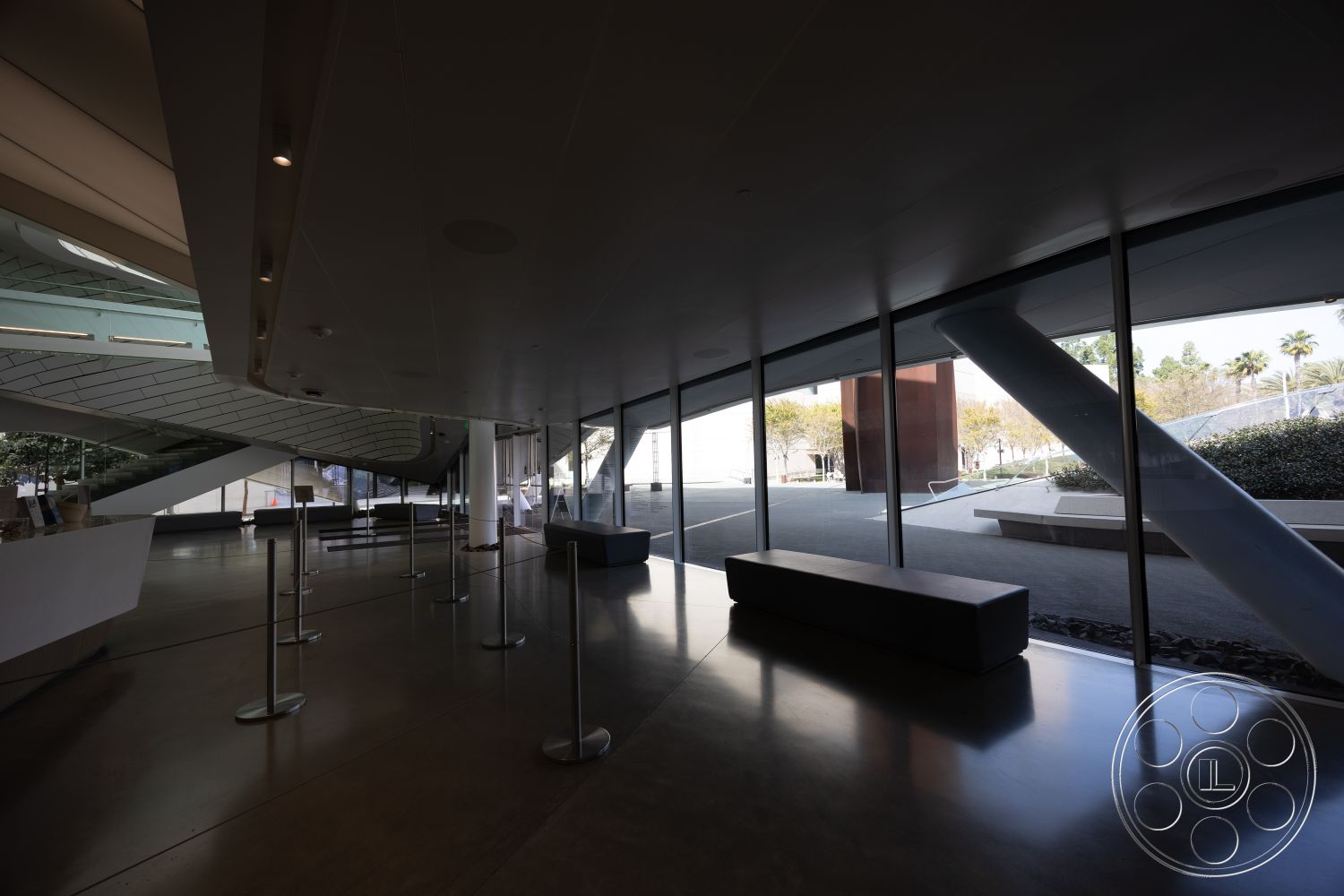 Museum 4 - open floor plan, polished concrete flooring, commercial space, monochromatic color scheme, exposed structural columns, interior lobby space, curved ceiling design, glass curtain wall windows, interior wayfinding signage, multi-level seating arrangement, minimalist reception desk, geometric architectural elements, landscaped outdoor view, sleek modern bench seating, natural light flooding through windows, two-story atrium, passive solar design features, urban architectural design, environmentally sustainable materials, innovative structural solutions